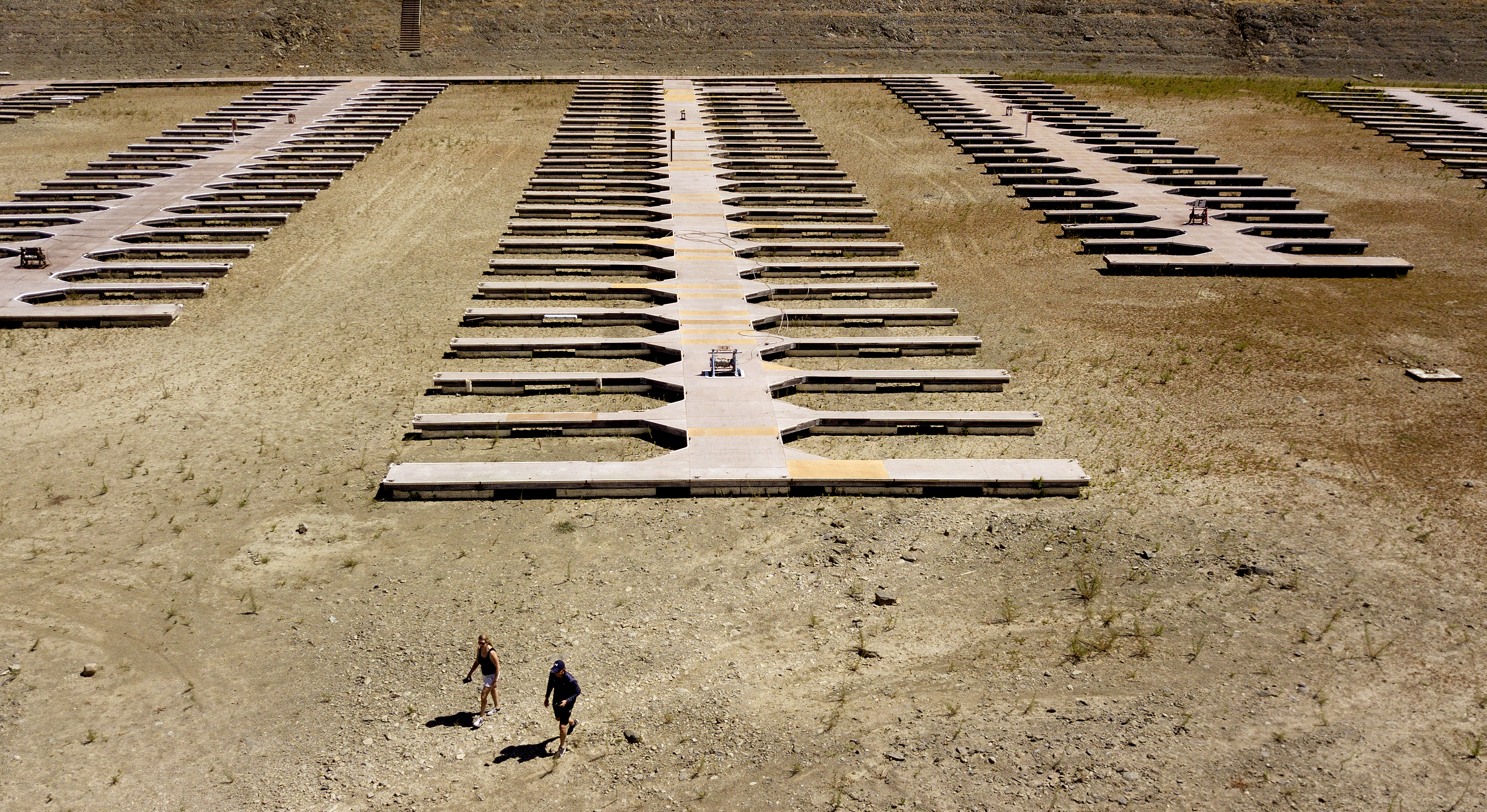 People walk near boat docks as they sit on dry land at the Browns Ravine Cove area of drought-stricken Folsom Lake. (AP Photo/Josh Edelson)