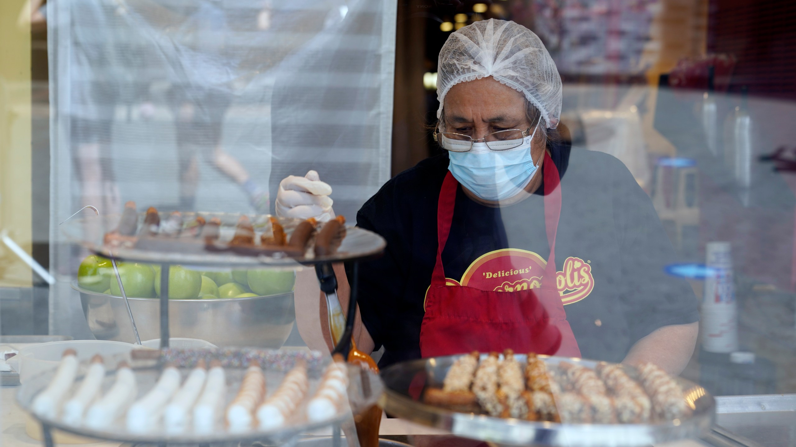 In this May 14, 2021, file photo, a worker wears a mask while prepares desserts at the Universal City Walk, in Universal City, Calif. California workplace regulators are considering Thursday, June 3, 2021, whether to end mask rules if every employee in a room has been fully vaccinated against the coronavirus, frustrating business groups by eying a higher standard than the state plans to soon adopt for social settings. (AP Photo/Marcio Jose Sanchez, File)