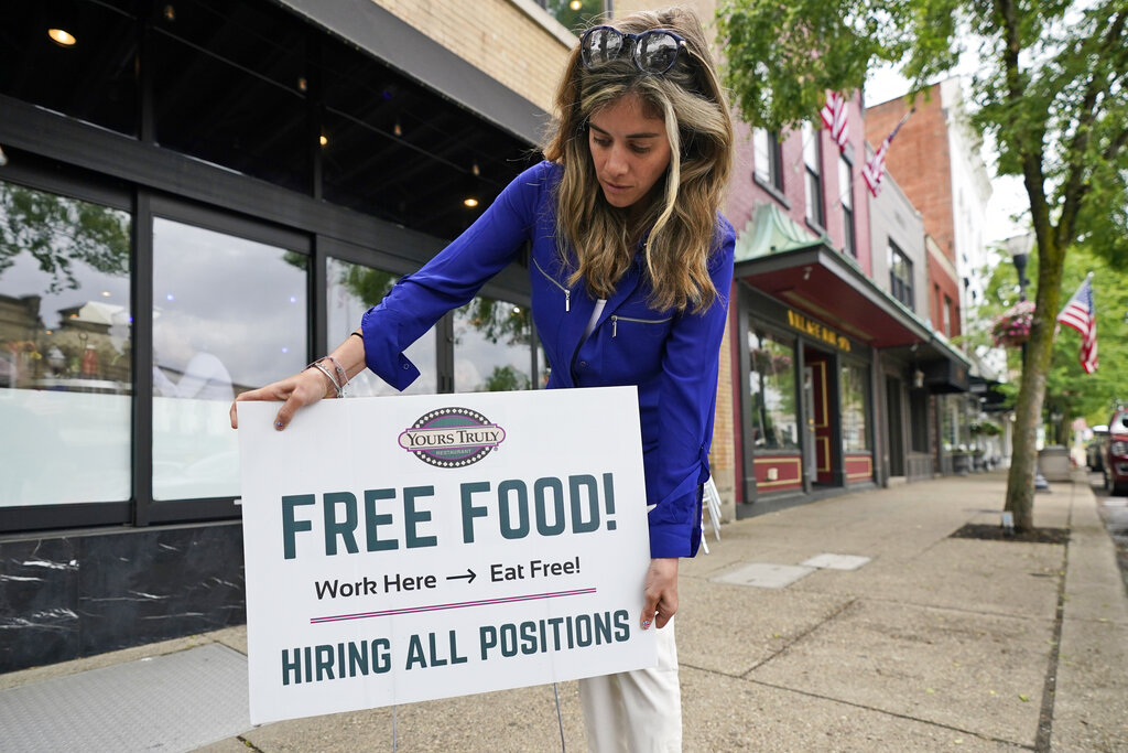 Coleen Piteo, director of marketing at Yours Truly restaurant, puts out a sign for hiring, Thursday, June 3, 2021, in Chagrin Falls, Ohio. (AP Photo/Tony Dejak)