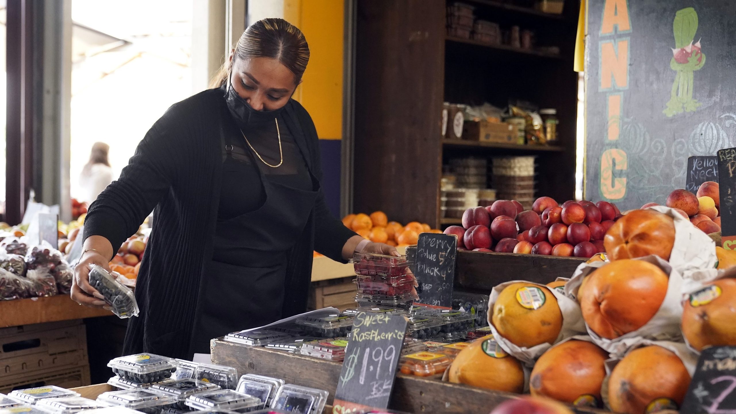 A worker wears a mask while setting up a fruit display amid the COVID-19 pandemic at The Farmers' Market in Los Angeles on May 20, 2021. (Marcio Jose Sanchez / Associated Press)