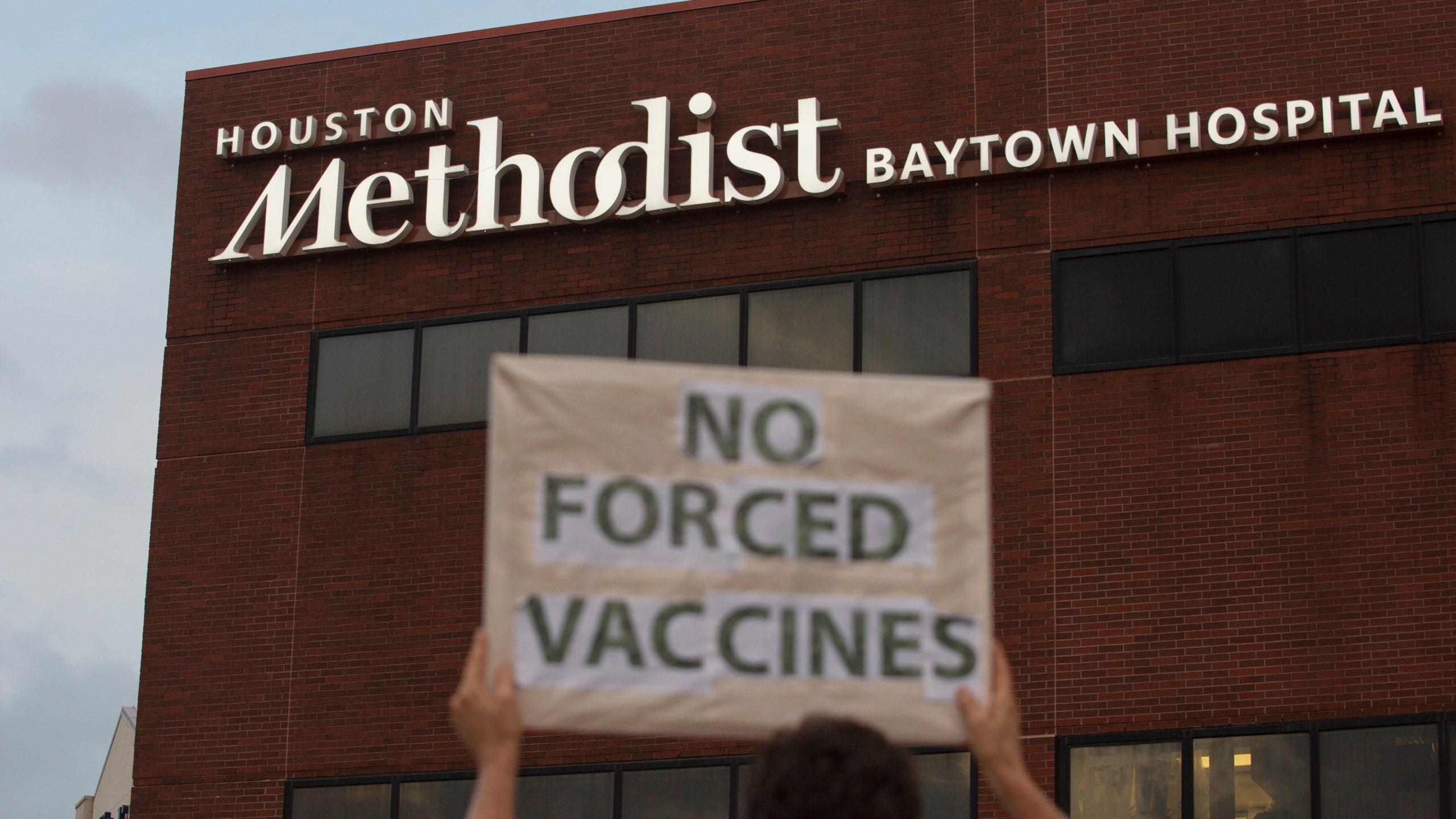 People bring signs to protest Houston Methodist Hospital system's rule of firing any employee who is not immunized by Monday, June 7, 2021, at Houston Methodist Baytown Hospital in Baytown, Texas. Houston Methodist staff who have refused the COVID-19 vaccine so far and their supporters participated in a gathering and march. (Yi-Chin Lee/Houston Chronicle via AP)