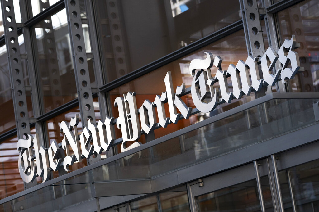 In this Thursday, May 6, 2021 file photo, a sign for The New York Times hangs above the entrance to its building, in New York. (AP Photo/Mark Lennihan, File)