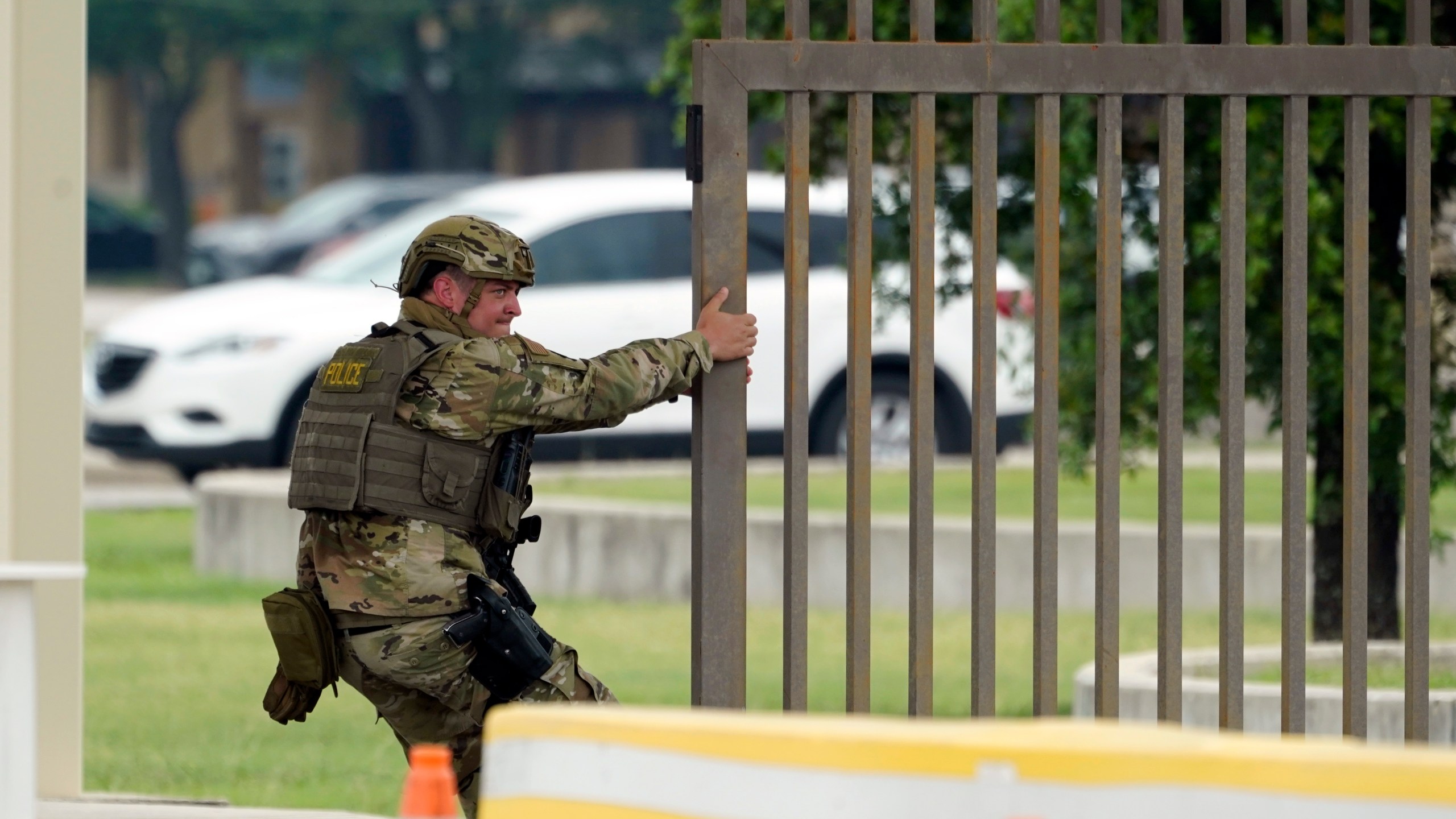 A military policeman closes a gate at JBSA-Lackland Air Force Base, Wednesday, June 9, 2021, in San Antonio. The Air Force was put on lockdown as police and military officials say they searched for two people suspected of shooting into the base from outside. (AP Photo/Eric Gay)