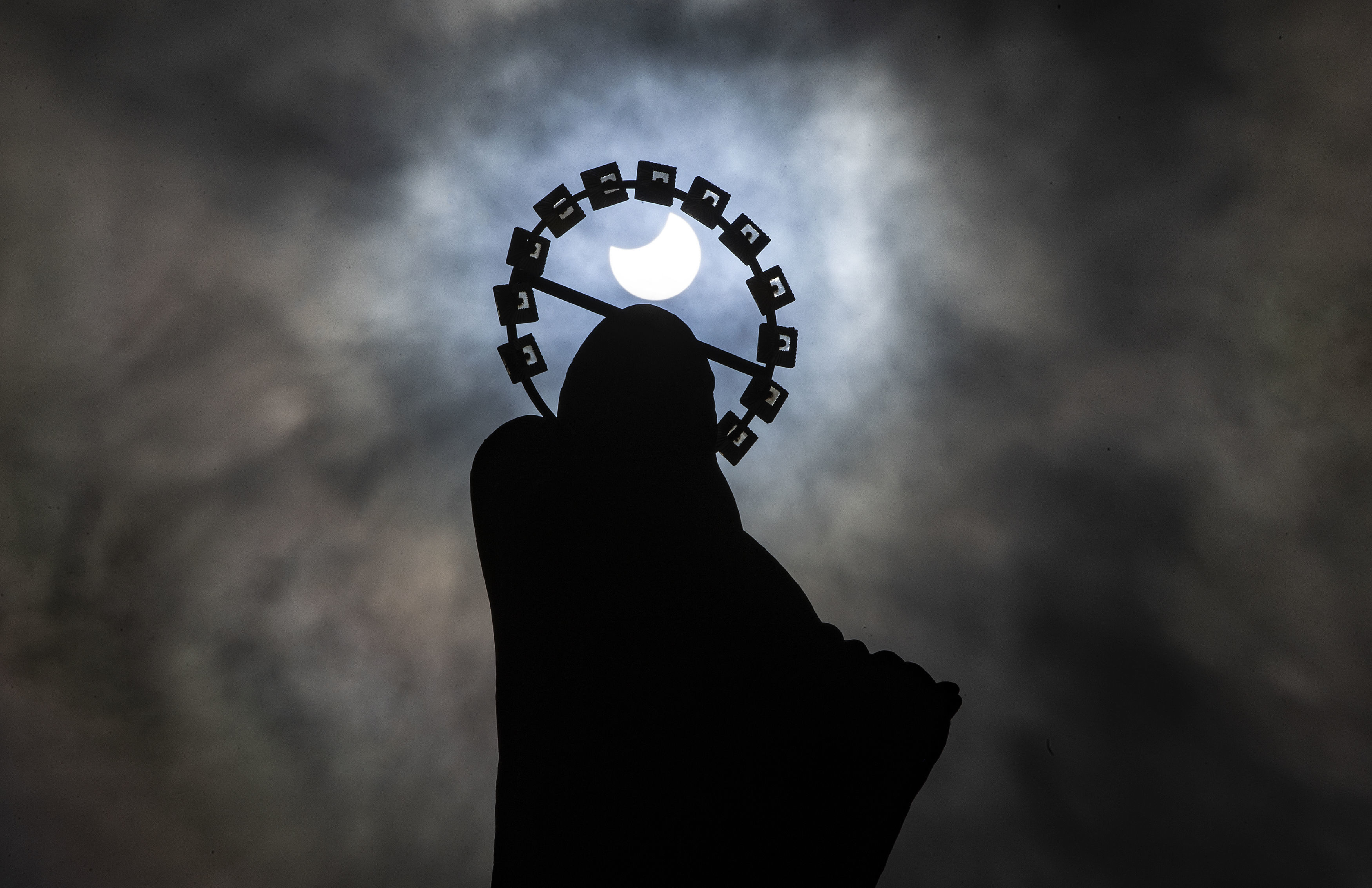 A statue of Our Lady, Star Of The Sea on Bull Wall in Dublin, is silhouetted against the sky during a partial solar eclipse, Thursday, June 10, 2021. (Brian Lawless/PA via AP)