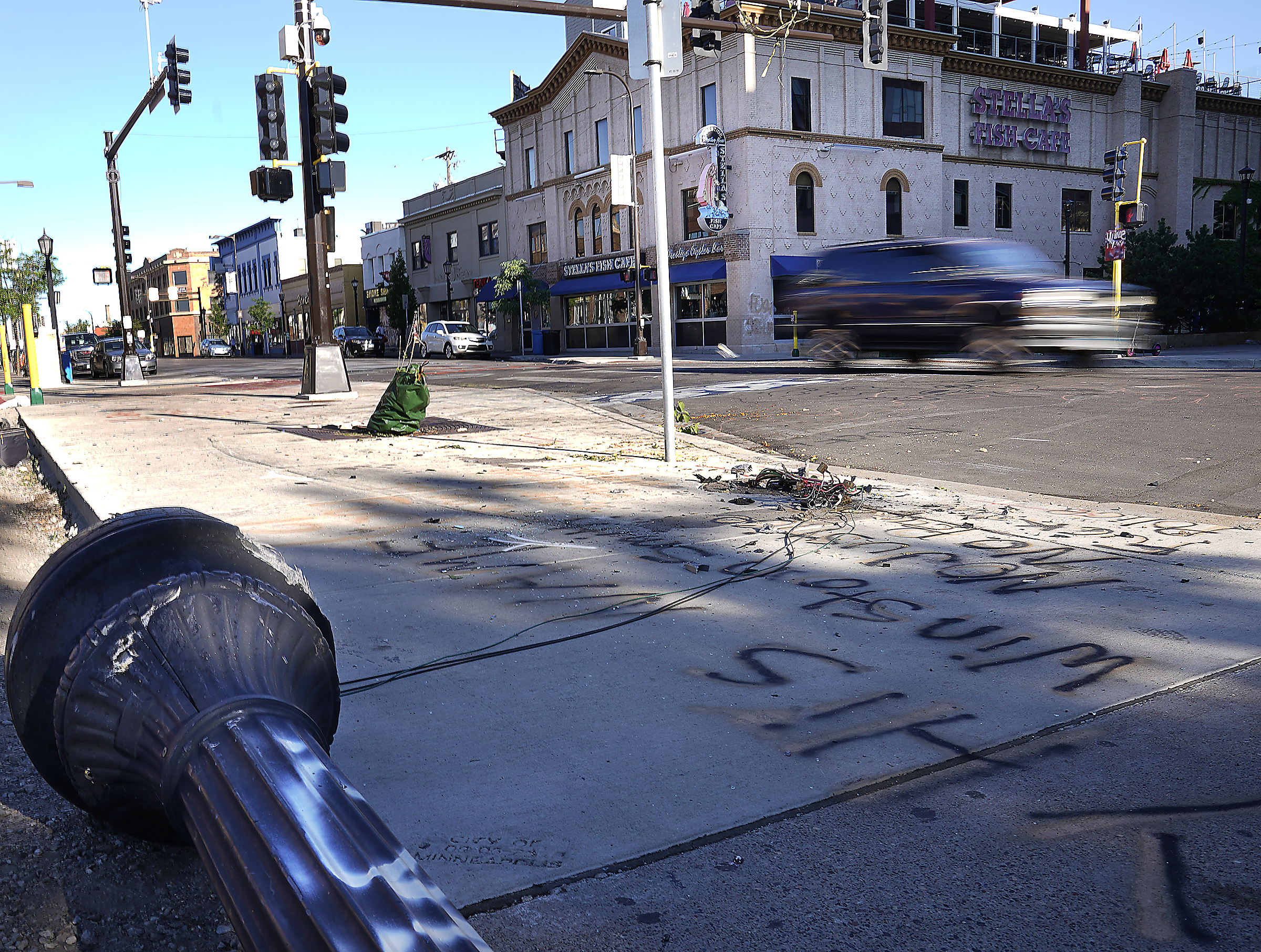 A car drives past the scene Monday, June 14, 2021, where police and witnesses say a woman was killed and multiple others were injured when an SUV struck a parked car and tossed it into demonstrators during a protest late Sunday in Uptown Minneapolis. (David Joles/Star Tribune via AP)