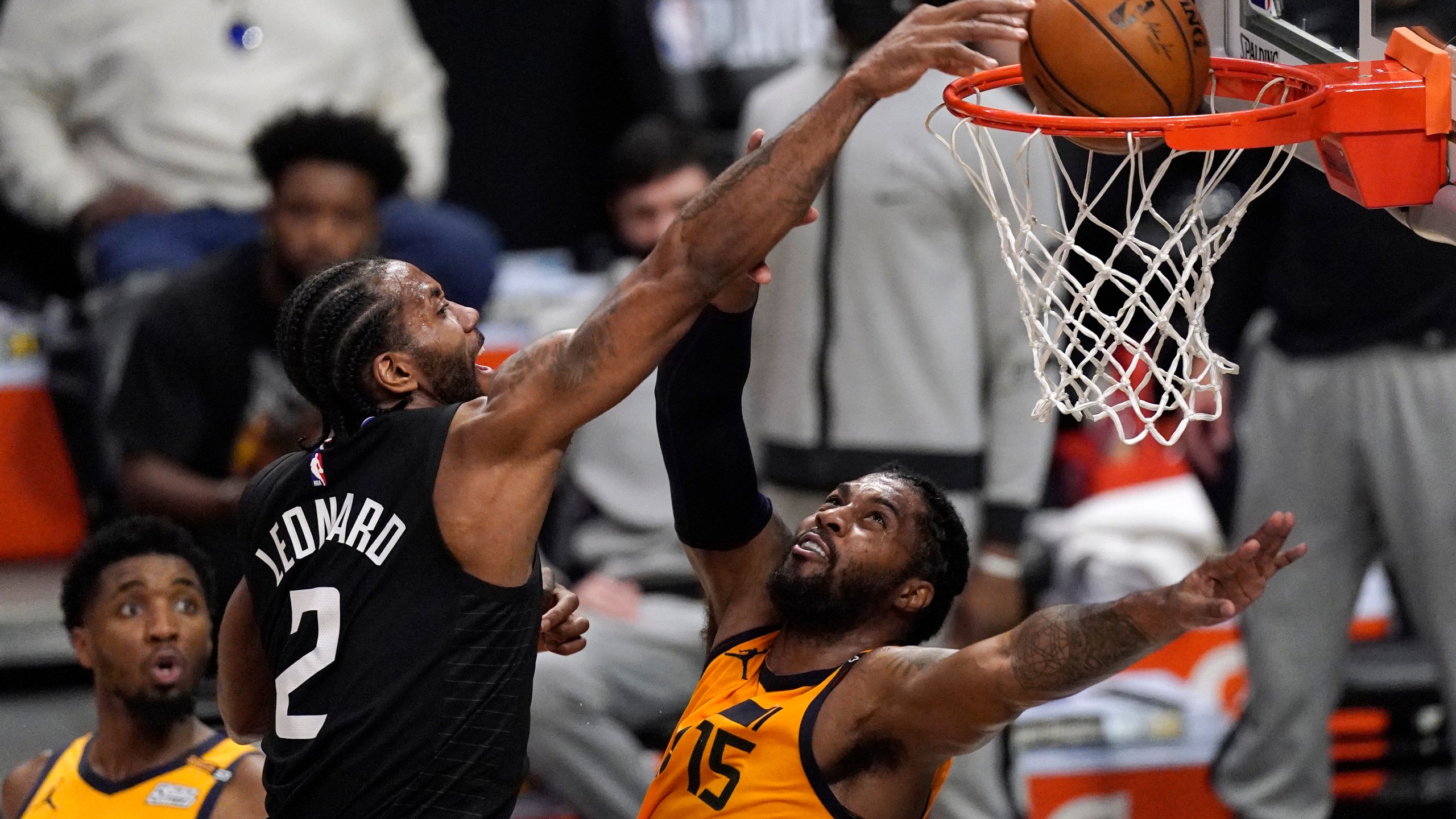 Los Angeles Clippers forward Kawhi Leonard, center, dunks over Utah Jazz center Derrick Favors, right, as guard Donovan Mitchell watches during the first half in Game 4 of a second-round NBA basketball playoff series on June 14, 2021, in Los Angeles. (Mark J. Terrill / Associated Press)