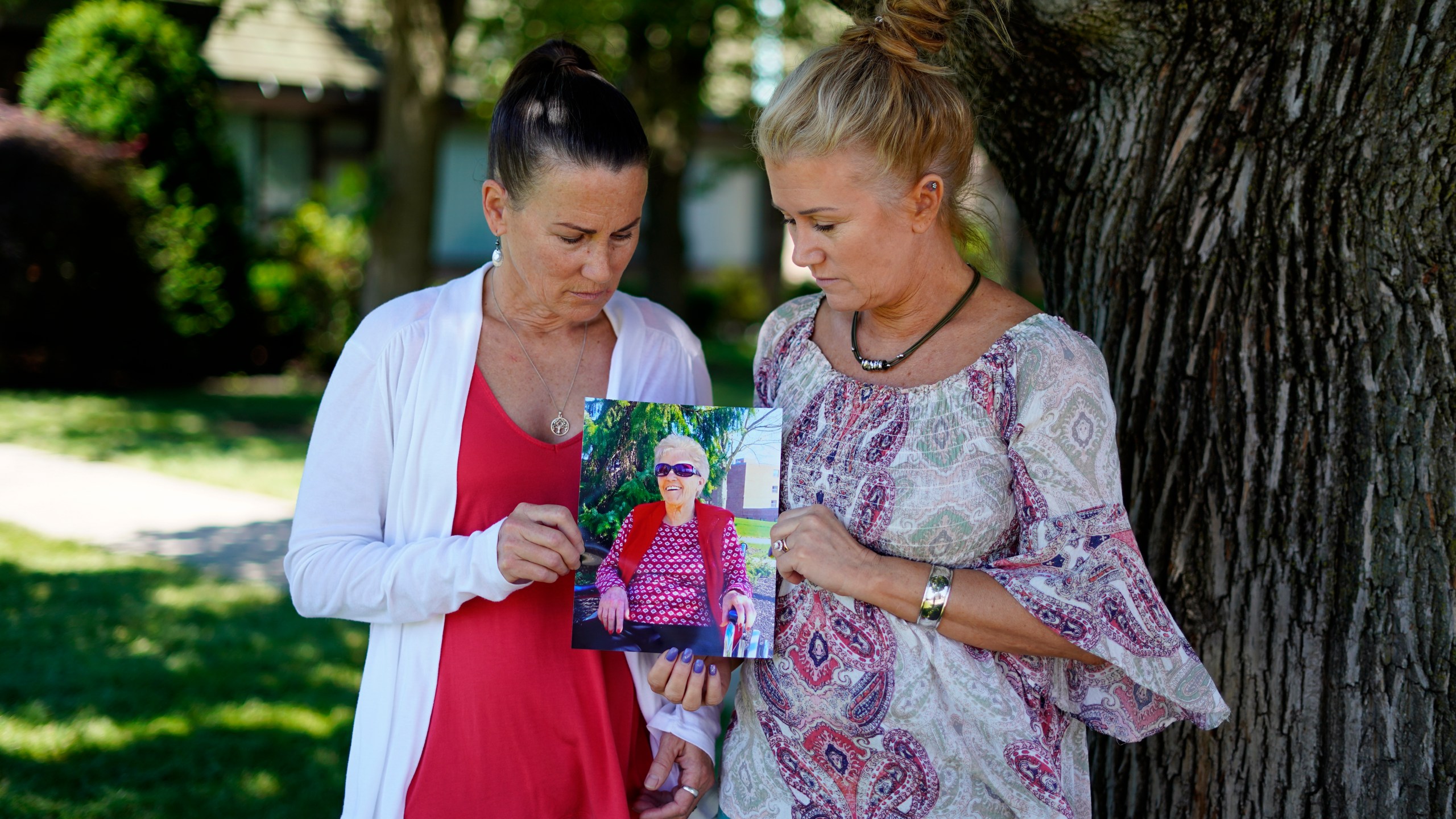 Angela Ermold, right, and her sister, Denise Gracely, hold a photo of their mother, Marian Rauenzahn, Thursday, June 17, 2021, in Fleetwood, Pa. (AP Photo/Matt Slocum)