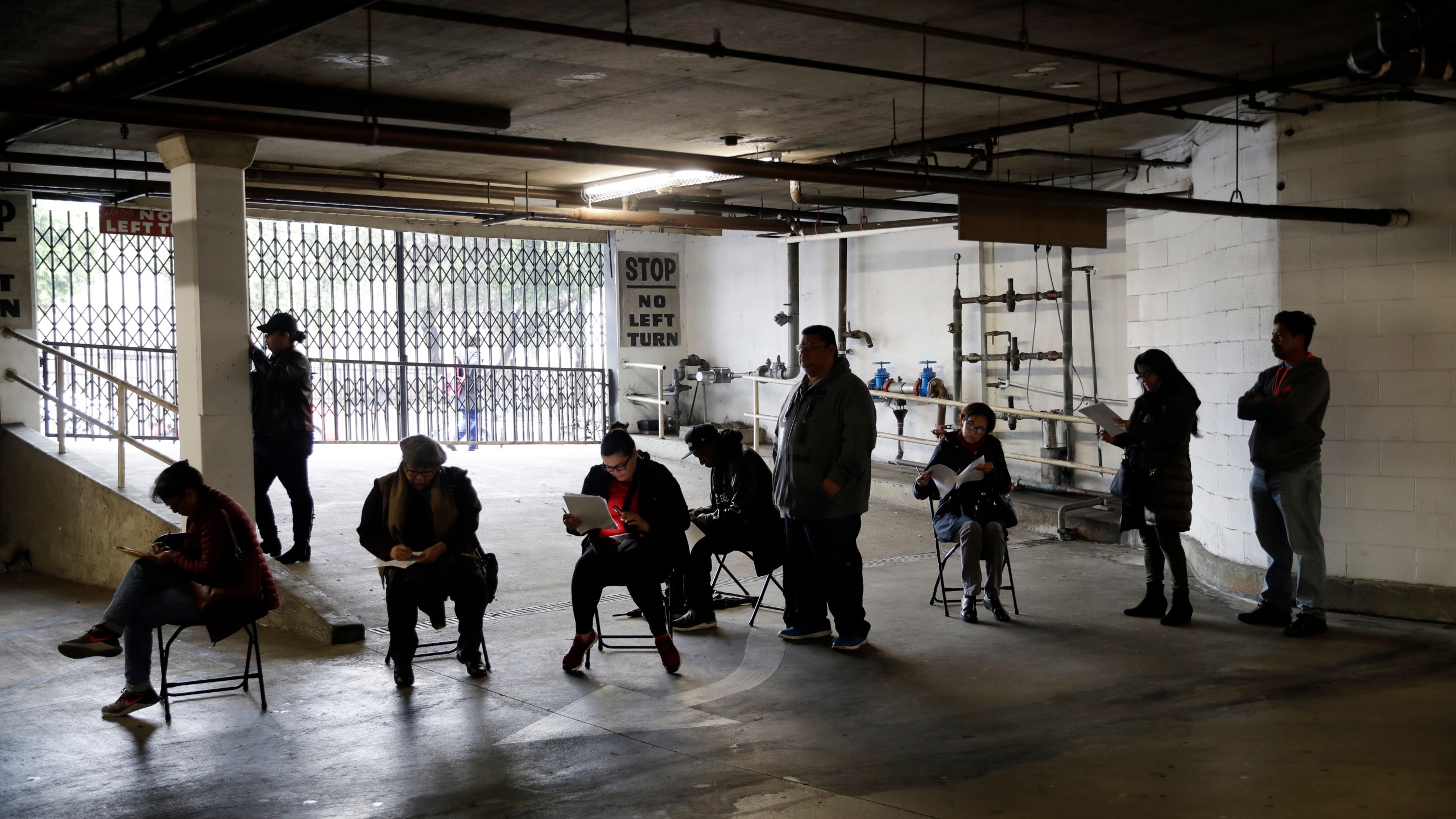 Unionized hospitality workers wait in line in a basement garage to apply for unemployment benefits at the Hospitality Training Academy in Los Angeles on March 13, 2020. (Marcio Jose Sanchez / Associated Press)