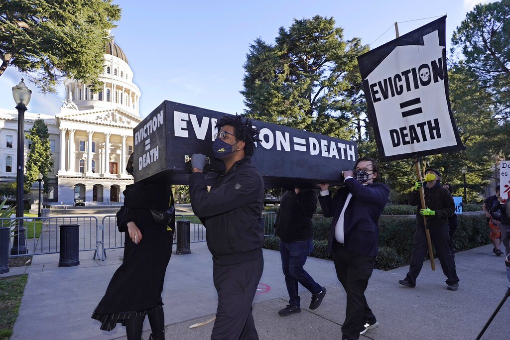 In this Jan. 25, 2021, file photo, demonstrators call passage of rent forgiveness and stronger eviction protections legislation and carry a mock casket past the Capitol in Sacramento, Calif. (AP Photo/Rich Pedroncelli, File)