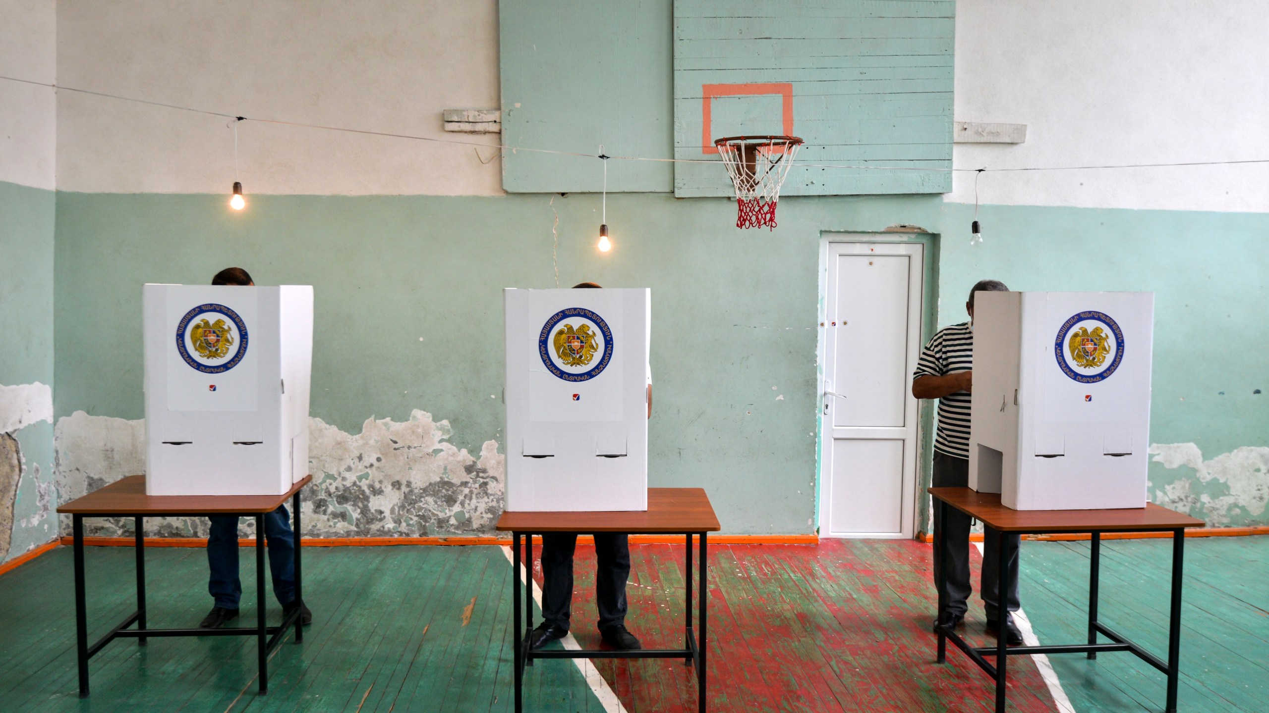 Voters read their ballots at a polling station in a school's sport hall during a parliamentary elections in Yerevan, Armenia, Sunday, June 20, 2021. (Karo Sahakyan/PAN Photo via AP)