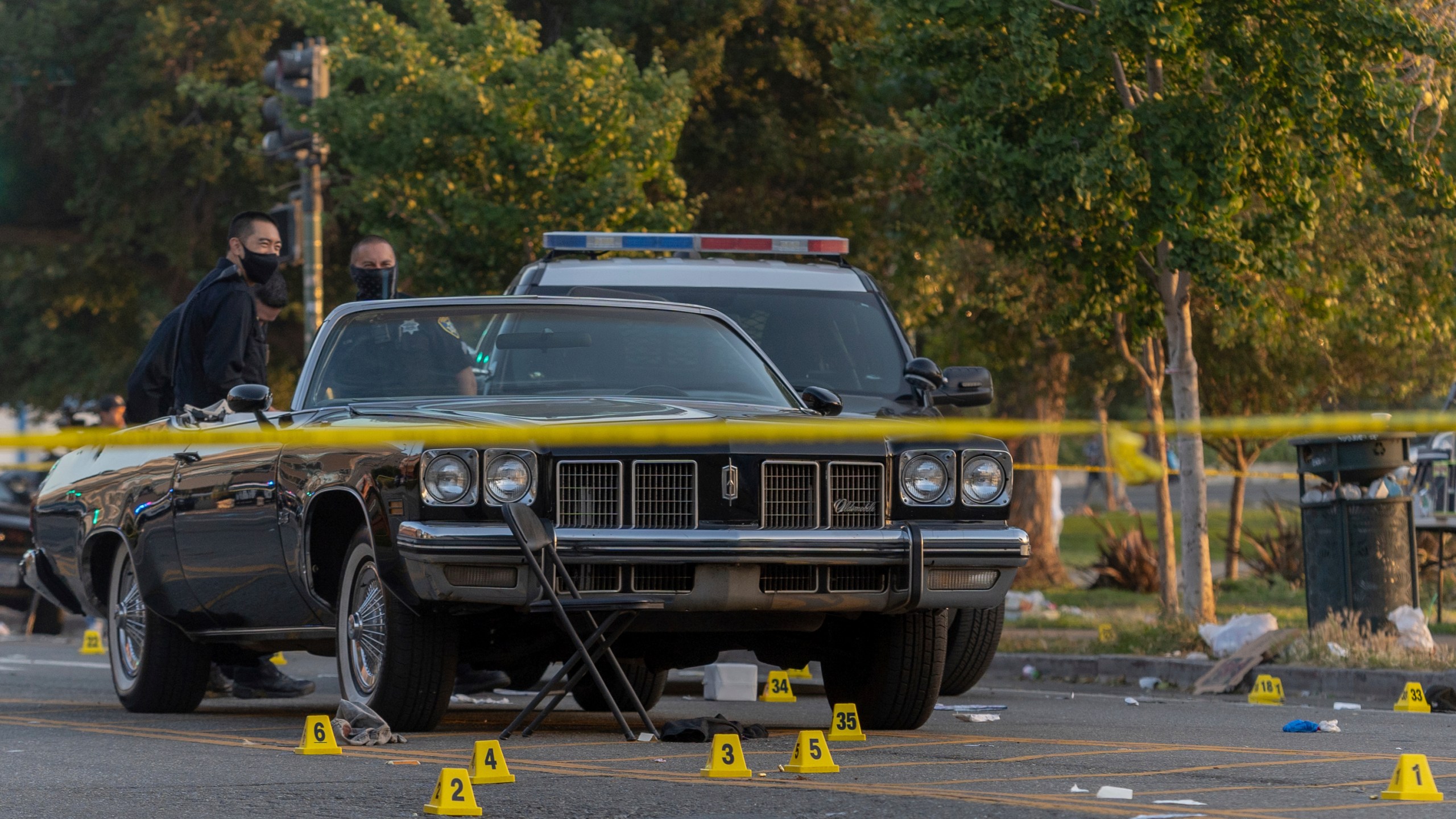 In this Saturday, June 19, 2021, photo, officers work the scene of a shooting in Oakland, Calif. A 22-year-old man was killed and five others were wounded in a shooting in Oakland near the city’s Juneteenth celebration, though it wasn't known whether the violence was connected with the event, police said. (Dylan Bouscher/Bay Area News Group)