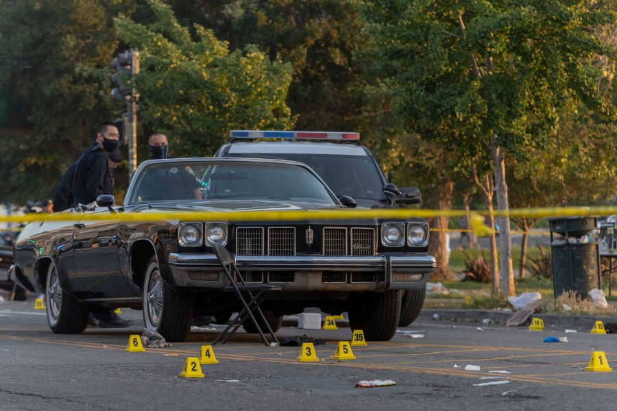 In this Saturday, June 19, 2021, photo, officers work the scene of a shooting in Oakland, Calif. A 22-year-old man was killed and five others were wounded in a shooting in Oakland near the city’s Juneteenth celebration, though it wasn't known whether the violence was connected with the event, police said. (Dylan Bouscher/Bay Area News Group)