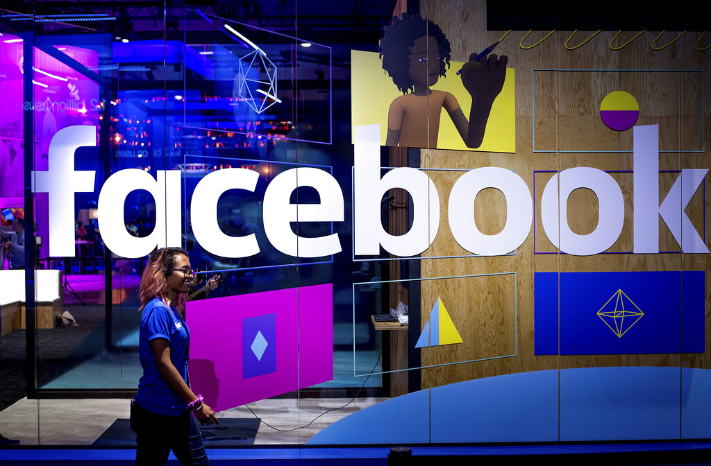 In this April 18, 2017, file photo, a conference worker passes a demo booth at Facebook's annual F8 developer conference, in San Jose, Calif. (AP Photo/Noah Berger, File)