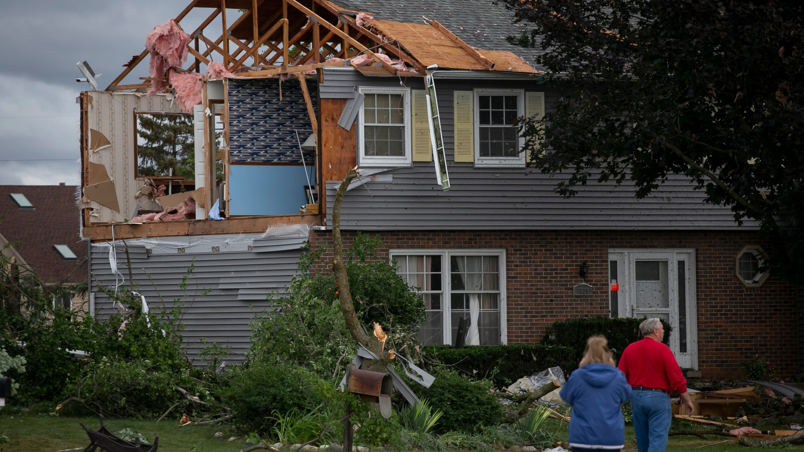 People walk near a damaged home on Princeton Circle in Naperville's Ranchview neighborhood after a tornado swept through the area, Monday, June 21, 2021, in Ill. (Rich Hein/Chicago Sun-Times via AP)