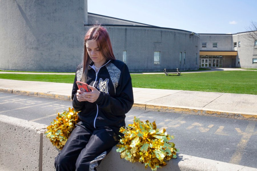 In this April 4, 2021, file photo provided by the American Civil Liberties Union, Brandi Levy wears her cheerleading outfit as she looks at her mobile phone outside Mahanoy Area High School in Mahanoy City, Pa. The Supreme Court ruled Wednesday, June 23, 2021, that the public school wrongly suspended Levy from cheerleading over a vulgar social media post she made after she didn't qualify for the varsity team. (Danna Singer/ACLU via AP, File)