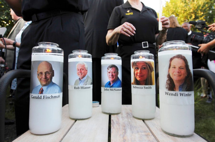 In this June 29, 2018, file photo, pictures of five employees of the Capital Gazette newspaper adorn candles during a vigil across the street from where they were slain in the newsroom in Annapolis, Md. (AP Photo/Jose Luis Magana, File)