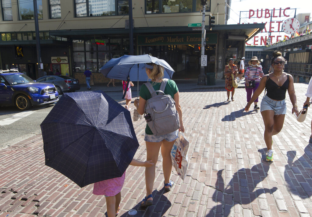 Sabina Ehmann and her daughter Vivian, visiting Seattle from North Carolina, are prepared with umbrellas to shield the sun during a heat wave hitting the Pacific Northwest, Sunday, June 27, 2021, in Seattle. (AP Photo/John Froschauer)