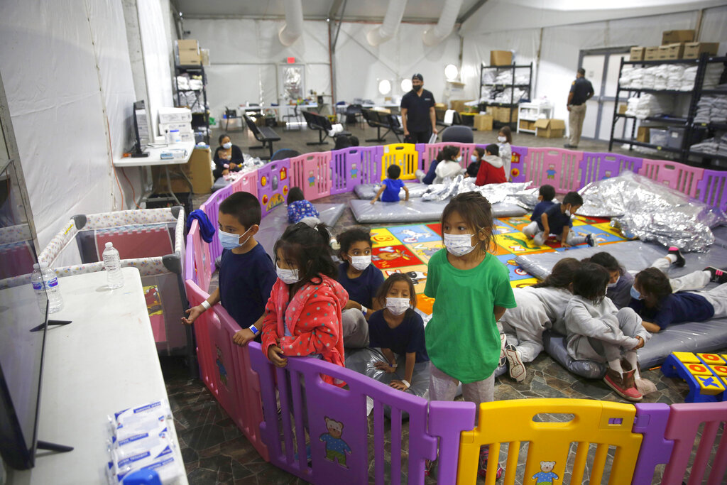 In this March 30, 2021 file photo Young unaccompanied migrants, from ages 3 to 9, watch television inside a playpen at the U.S. Customs and Border Protection facility, the main detention center for unaccompanied children in the Rio Grande Valley, in Donna, Texas. (AP Photo/Dario Lopez-Mills, Pool, File)