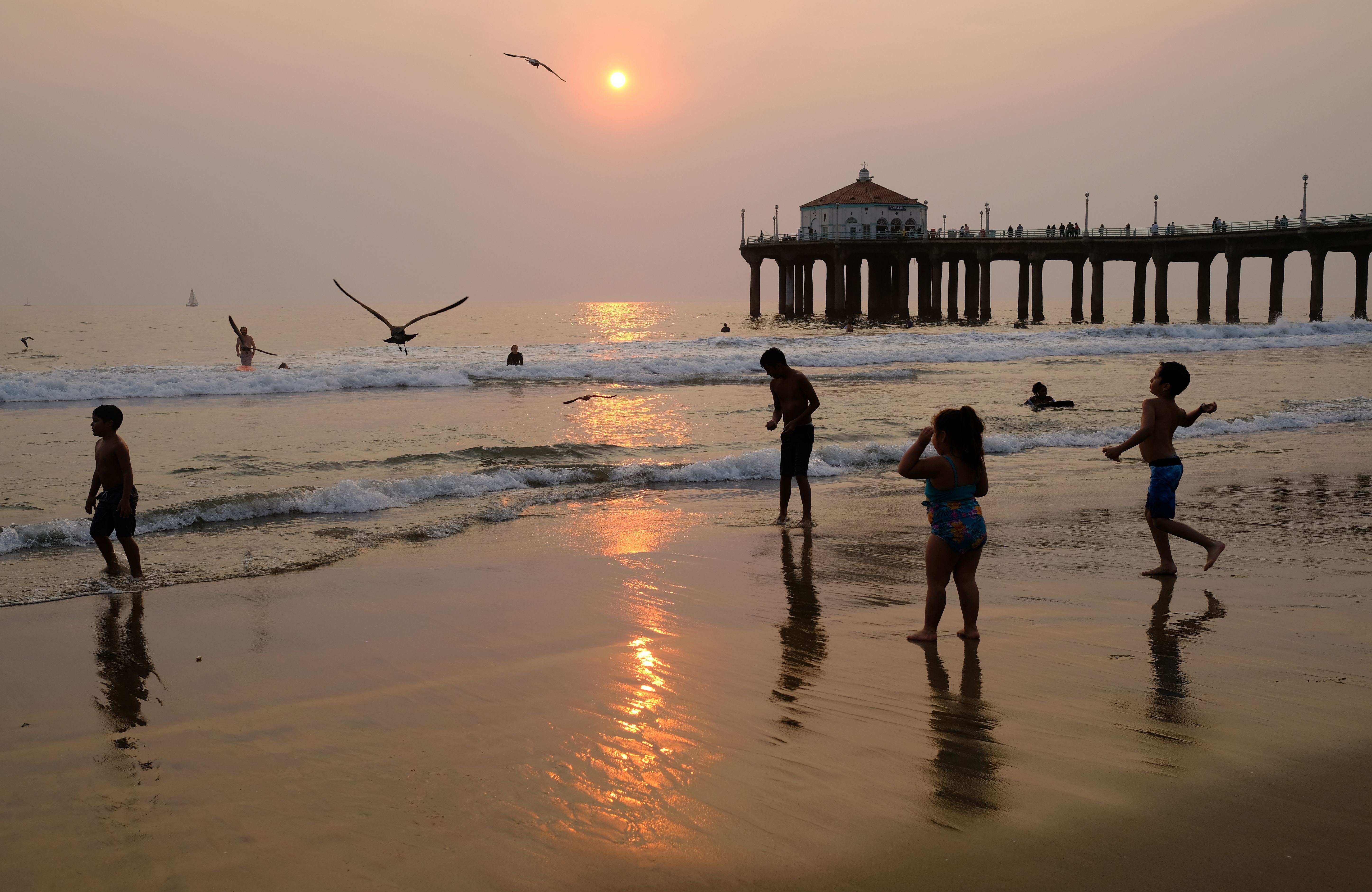 Children play in the water at sunset during a heat wave on September 7, 2020 in Manhattan Beach, California. (Chris Delmas/AFP via Getty Images)