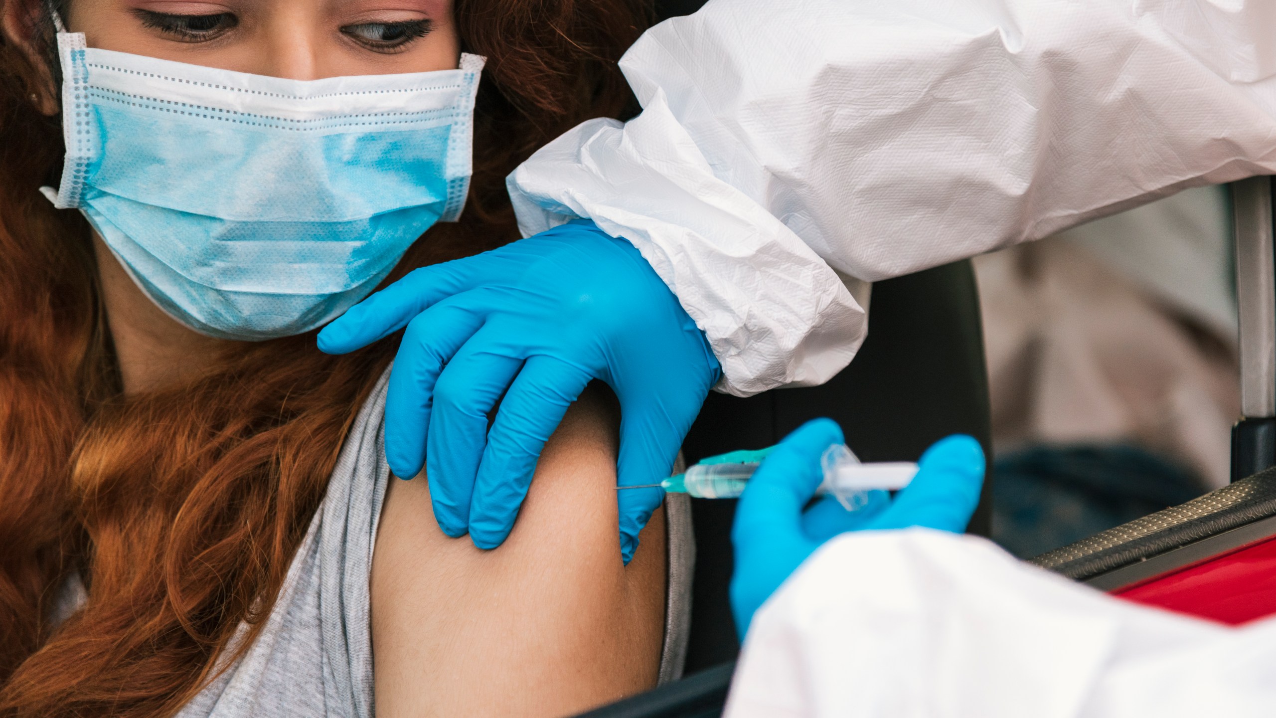 Nurse applying vaccine to patient in car. (Getty Images)