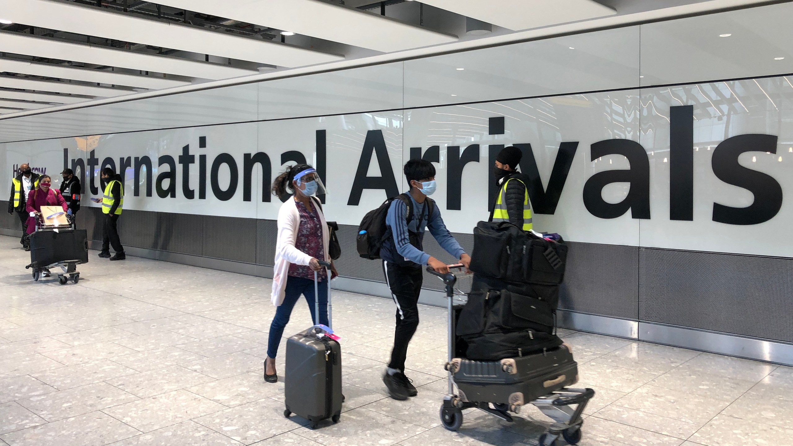 Passengers are escorted through the arrivals area of terminal 5 towards coaches destined for quarantine hotels, after landing at Heathrow airport on April 23, 2021 in London, England. (Leon Neal/Getty Images)