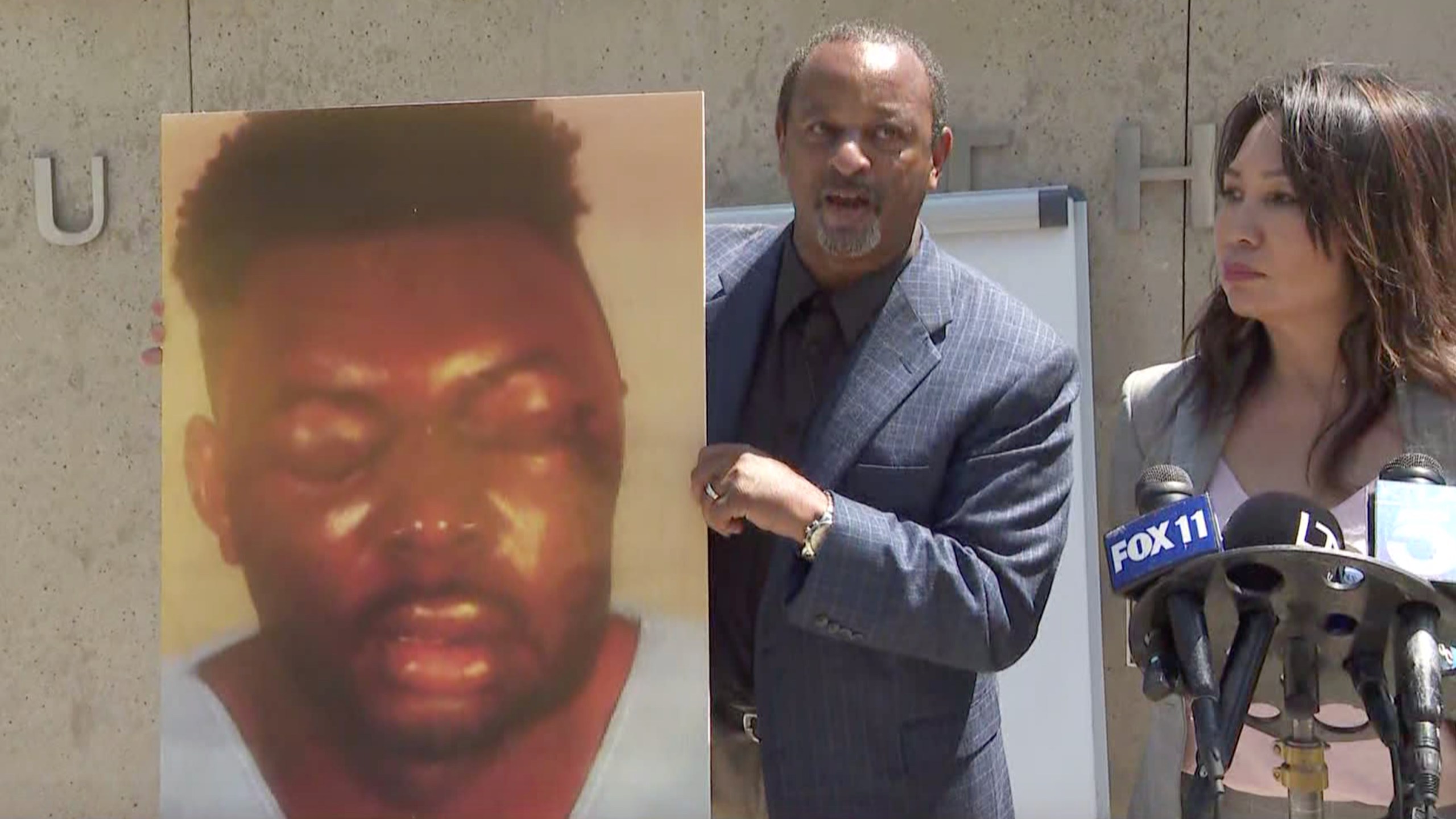 Attorneys Brian Dunn, left and Toni Jaramilla appear at a news conference in Century City on June 21, 2021, announcing a lawsuit against the Los Angeles County Sheriff’s Department. Dunn holds a picture of Christopher Bailey after an alleged beating by deputies in Inglewood.