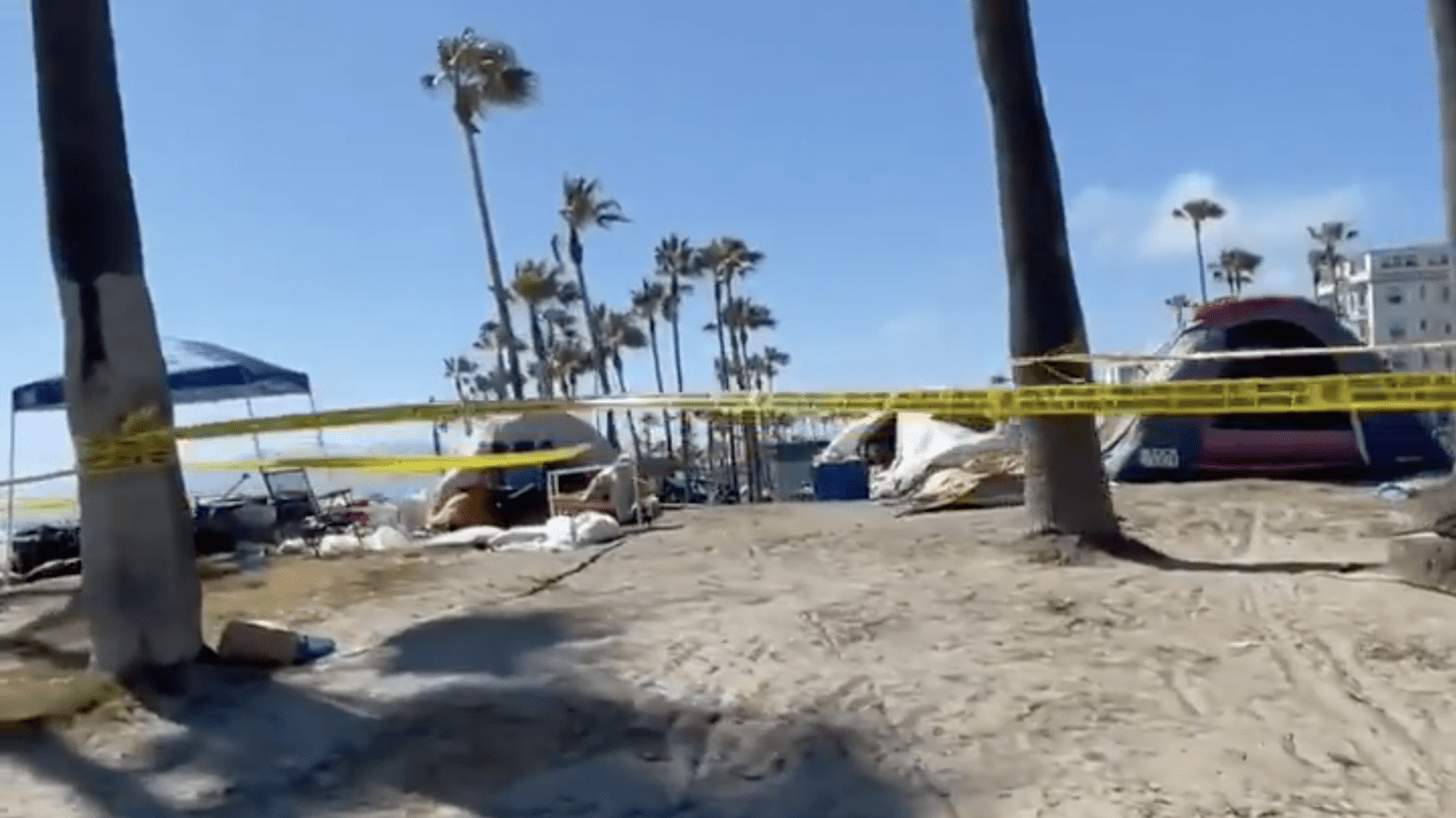 Part of a homeless encampment at Venice Beach is taped off for investigation after a man was found dead there on June 25, 2021. (@boardwalkvenice / Twitter)