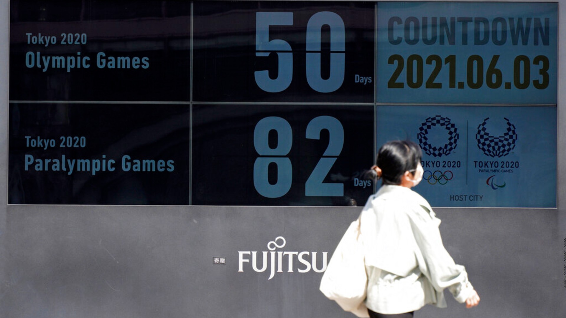 People walk past the countdown clock for the Tokyo 2020 Olympic and Paralympic Games near Shimbashi station in Tokyo, Thursday, June 3, 2021. (AP Photo/Kantaro Komiya)