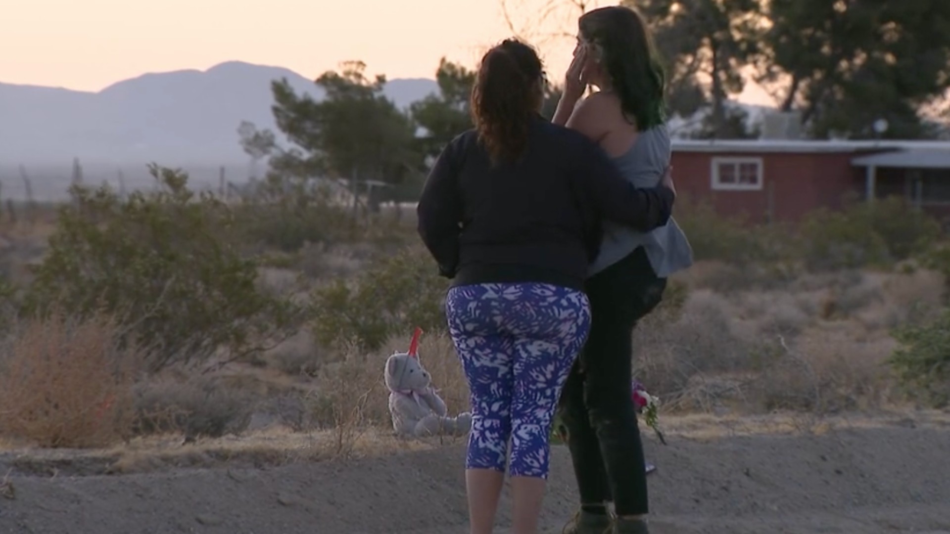 Two people gathered Monday near the site of a hit-and-run crash that took the lives of three girls who were on a late night stroll in Lucerne Valley. (KTLA)