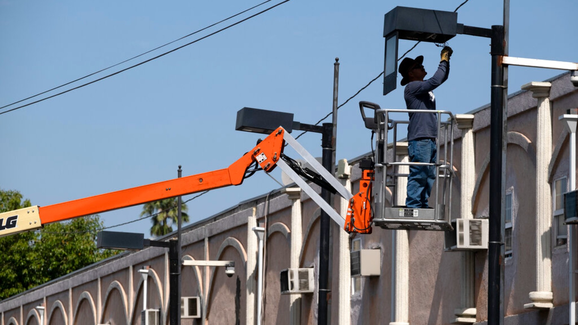 A worker fixes a street lamp in the Van Nuys section of Los Angeles on Thursday, June 17, 2021. (AP Photo/Richard Vogel)