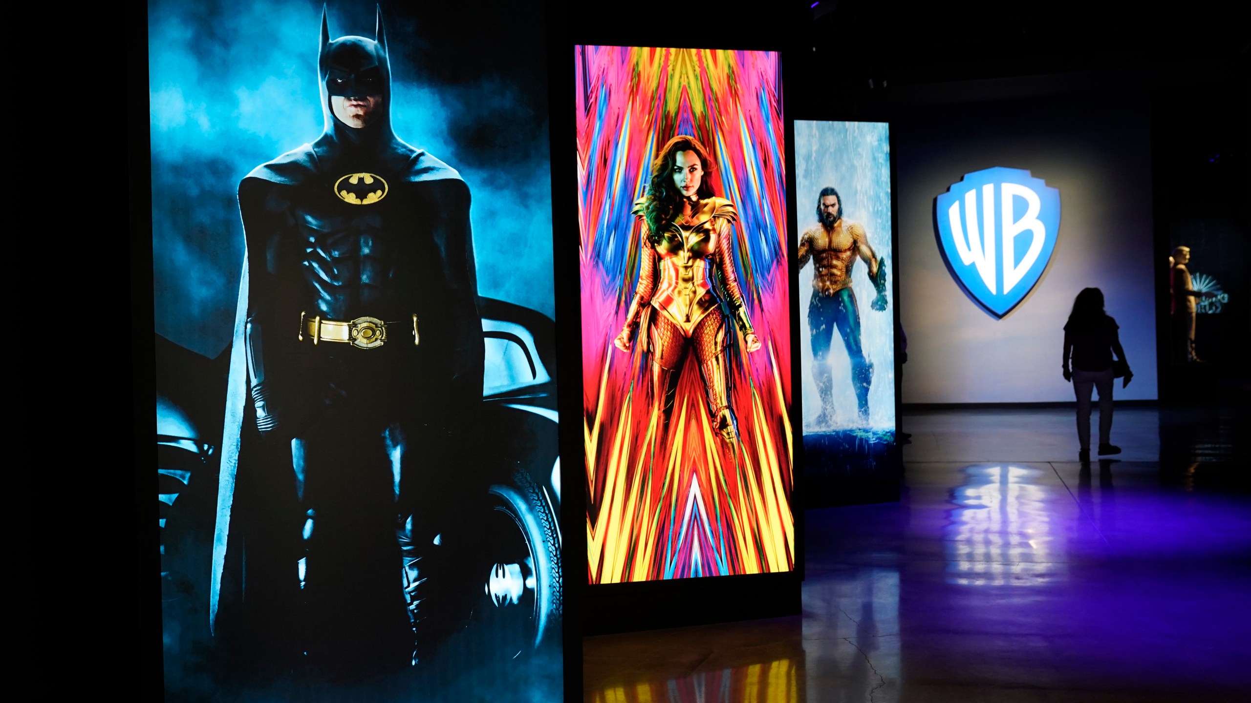 A visitor walks past portraits of DC Comics superheroes as she enters the "Action and Magic Made Here" interactive experience at the Warner Bros. Studio Tour Hollywood media preview on June 24, 2021, in Burbank, Calif. (AP Photo/Chris Pizzello)