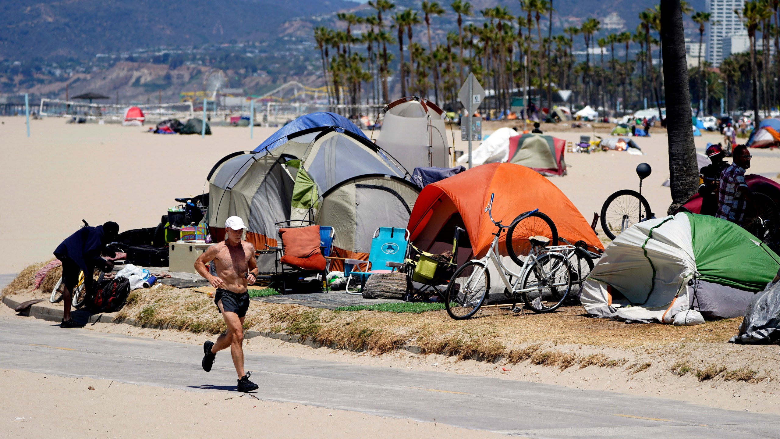 In this June 8, 2021, file photo, a jogger walks past a homeless encampment in the Venice Beach section of Los Angeles. (AP Photo/Marcio Jose Sanchez, File)