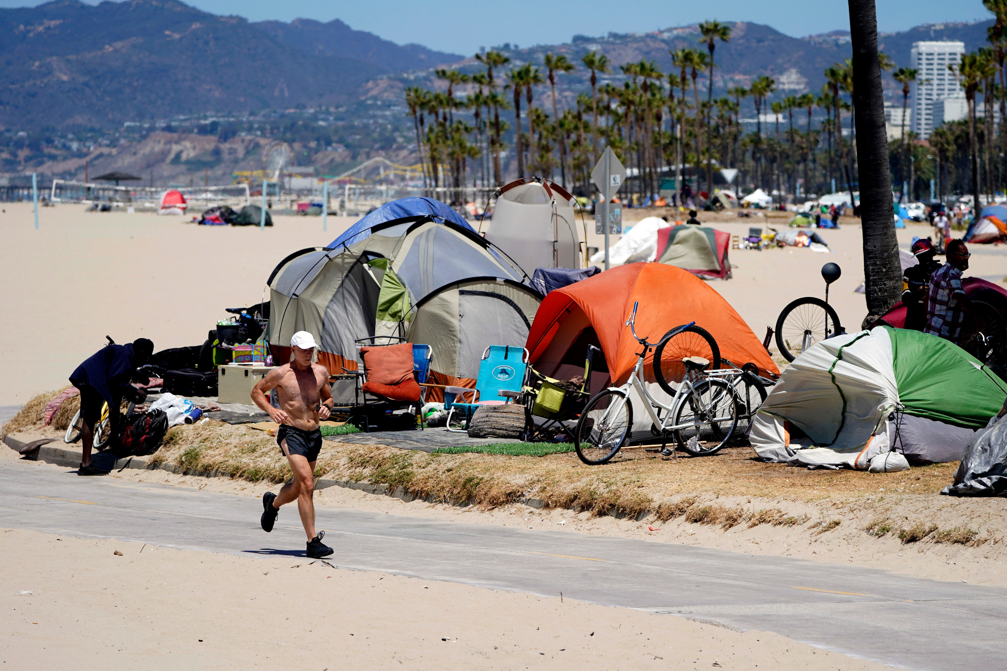 In this June 8, 2021, file photo, a jogger walks past a homeless encampment in the Venice Beach section of Los Angeles. (AP Photo/Marcio Jose Sanchez, File)