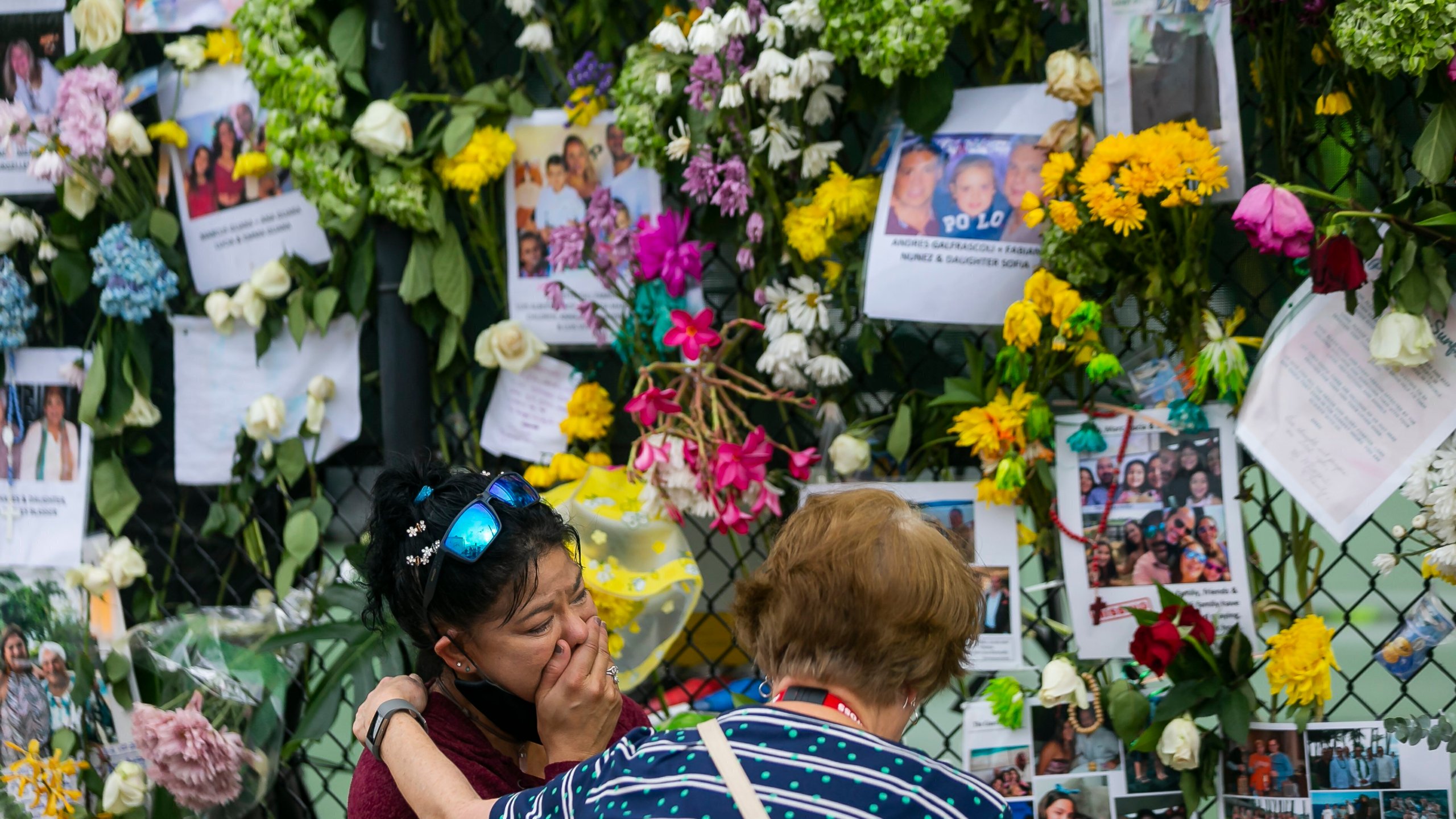 In this June 29, 2021, file photo, mourners visit a makeshift memorial near the site of the collapsed condominium in Surfside, Fla. While hundreds of rescuers search desperately for survivors within the rubble of the collapsed condominium, a smaller cadre of mental health counselors are also deploying to help families and other loved ones cope with the tragedy. (Matias J. Ocner/Miami Herald via AP, File)