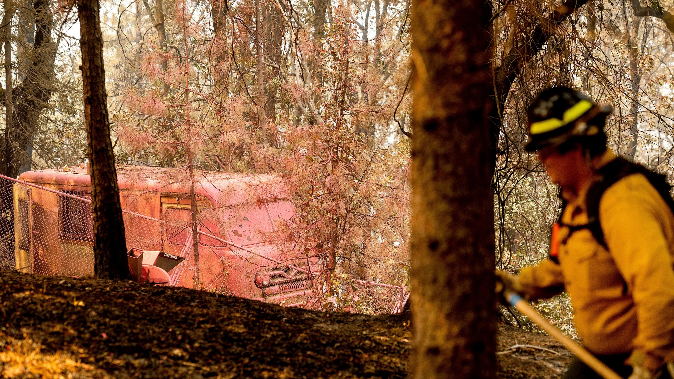 Raymond Vasquez, a firefighter with Wildfire Defense Systems, extinguishes hot spots in the Lakehead-Lakeshore community of unincorporated Shasta County, Calif., as the Salt Fire burns nearby on Friday, July 2, 2021. (AP Photo/Noah Berger)