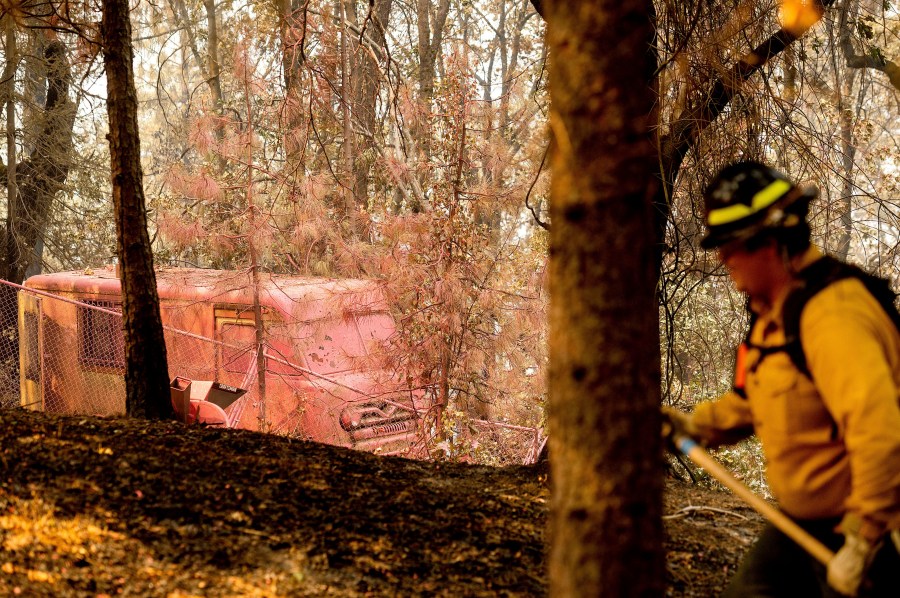 Raymond Vasquez, a firefighter with Wildfire Defense Systems, extinguishes hot spots in the Lakehead-Lakeshore community of unincorporated Shasta County, Calif., as the Salt Fire burns nearby on Friday, July 2, 2021. (AP Photo/Noah Berger)