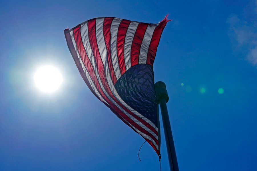 In this Wednesday, June 30, 2021 photo, a U.S. flag flies with the sun in the background in downtown Seattle. (AP Photo/Ted S. Warren, File)