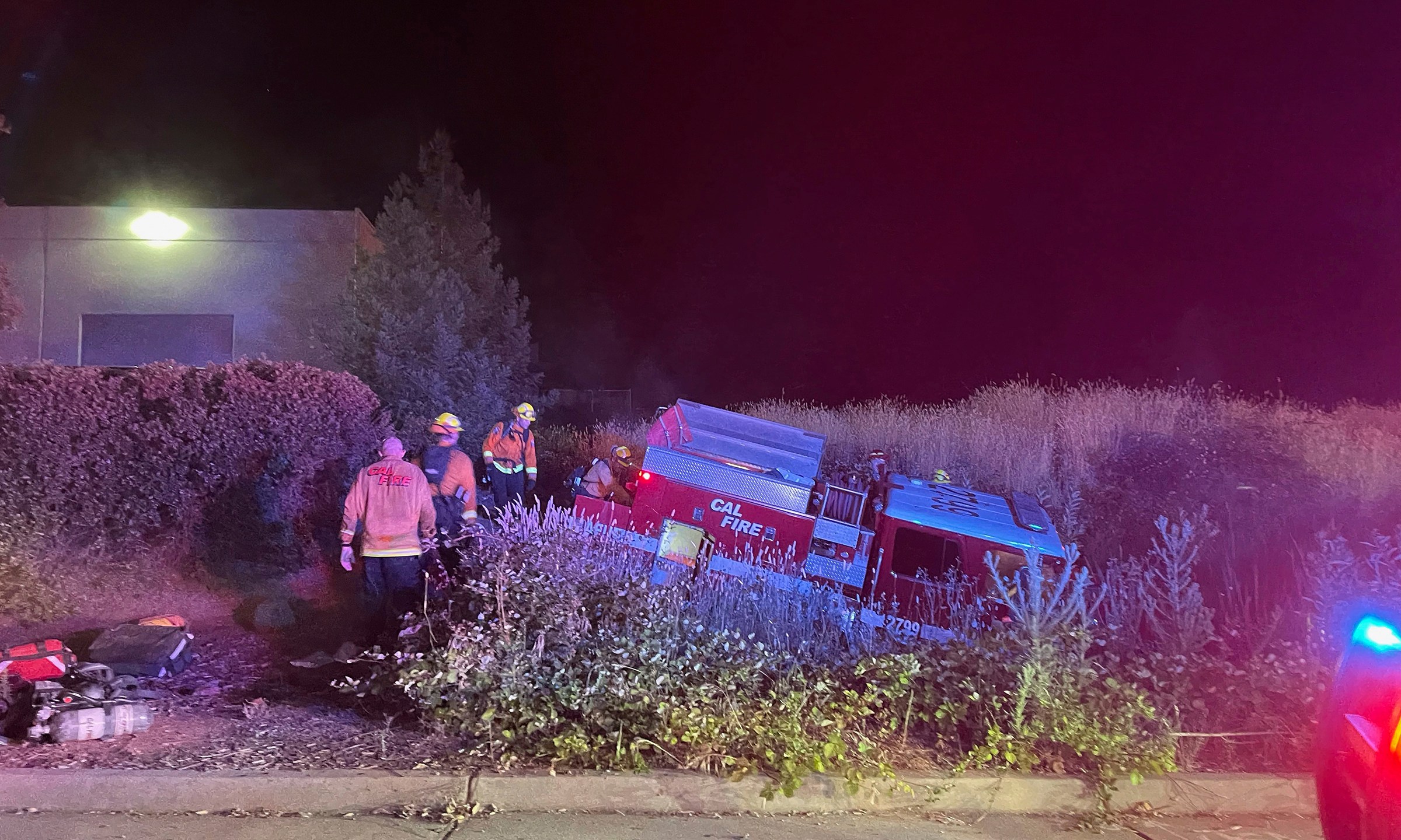 In this photo provided by Bill Wilde, firefighters look over a California Department of Forestry and Fire Protection truck that crashed into a ditch after it was stolen by a California inmate on July 4, 2021, in Shingle Springs, Calif. (Bill Wilde Photo via AP)