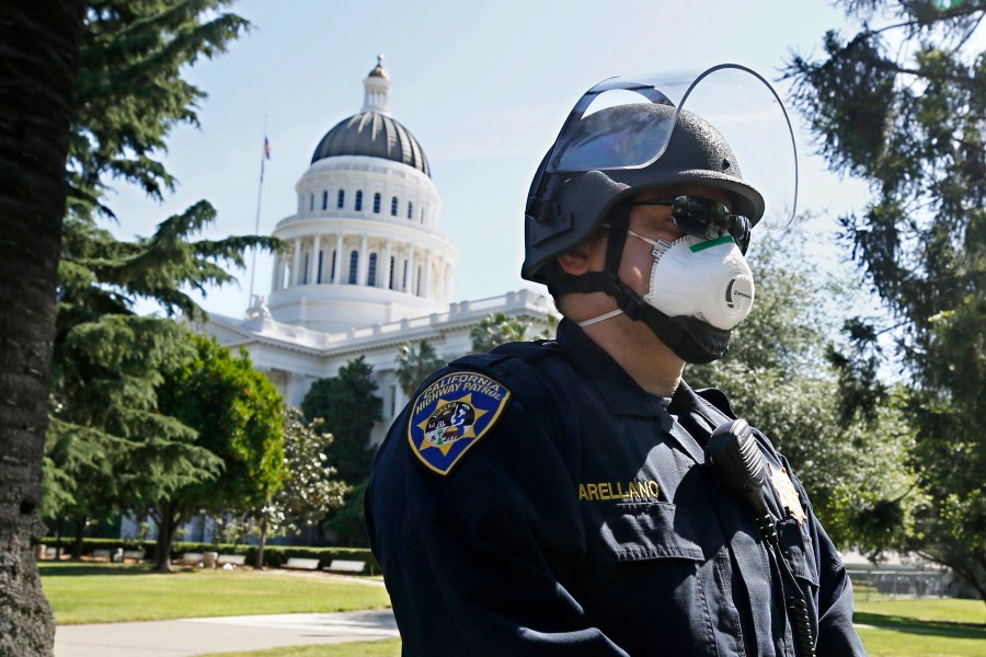 California Highway Patrol Officer S. Arellano wears a face mask as he and other officers form a line in anticipation of a protest at the the state Capitol in Sacramento on May 7, 2020. (Rich Pedroncelli / Associated Press)