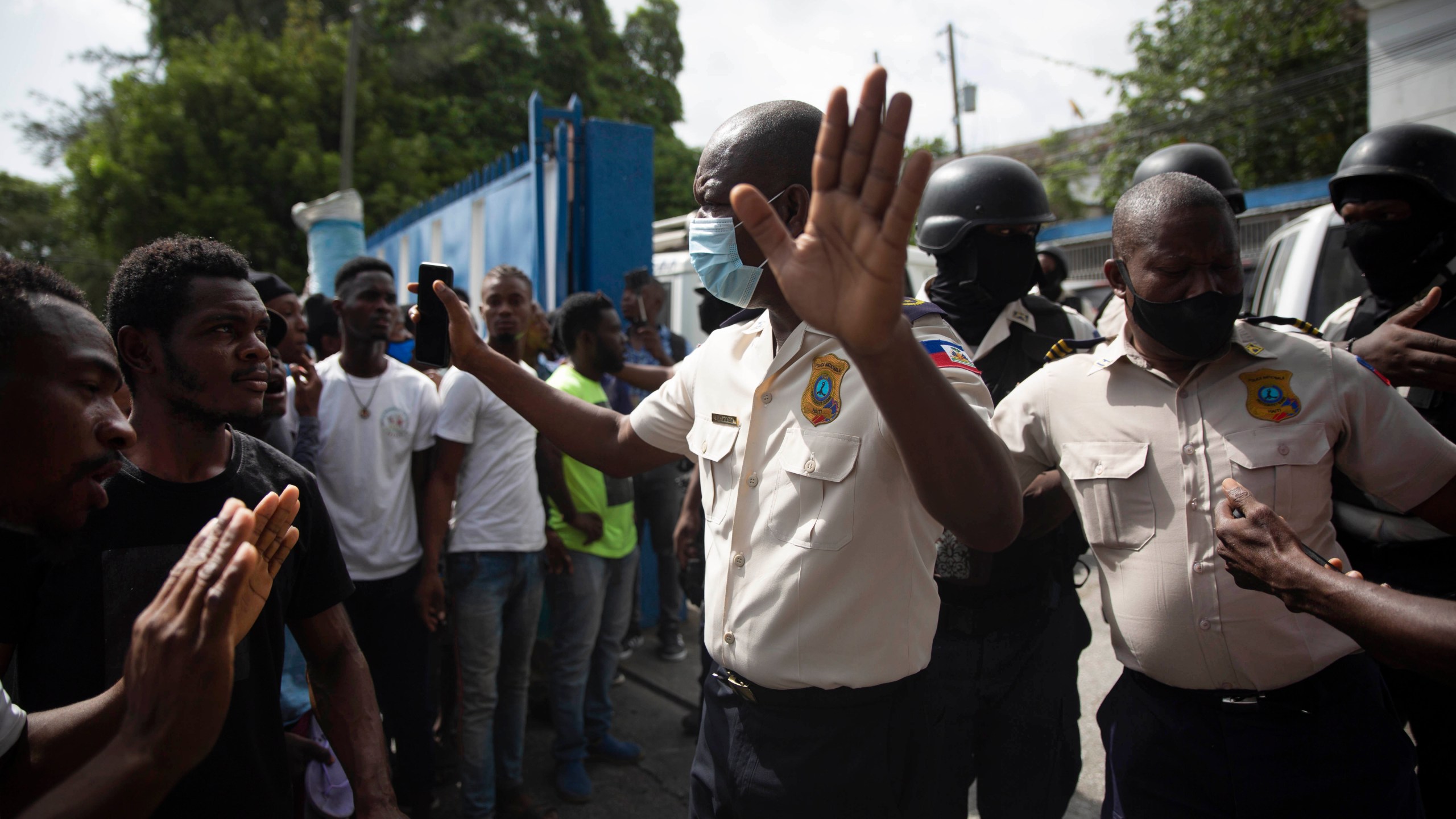 People pressure police to hand over two men who were arrested and the bodies of two men who were brought in by police after they were killed by police, in order to burn them in retaliation for the assassination of Haitian President Jovenel Moïse, at a police station of Petion Ville in Port-au-Prince, Haiti, Thursday, July 8, 2021. According to National Police Director Leon Charles, the dead and detained are suspects in Moïse's July 7 assassination. (AP Photo/Joseph Odelyn)