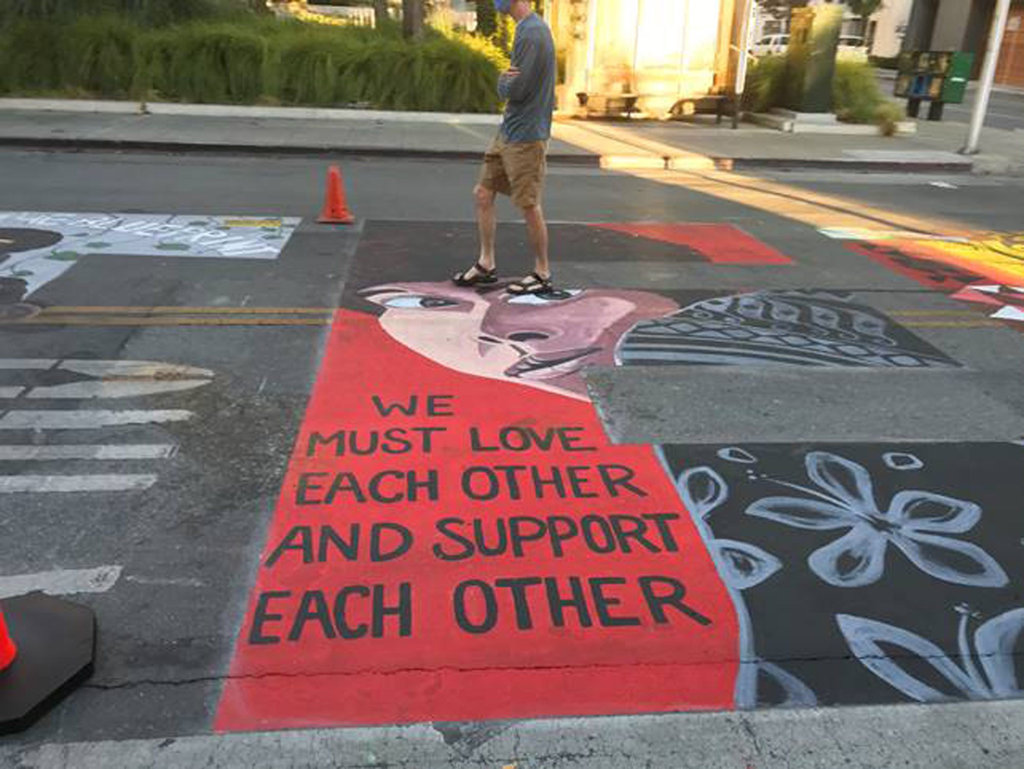 In this photo provided by the Palo Alto Daily Post, a man walks by a Black Lives Matter mural showing Assata Shakur, who was convicted of killing a New Jersey law enforcement officer in 1973, on July 8, 2020, in Palo Alto, Calif. Five police officers have filed a lawsuit against the city of Palo Alto for allowing the creation of the mural they say contained anti-police images. (Dave Price/Palo Alto Daily Post via AP)