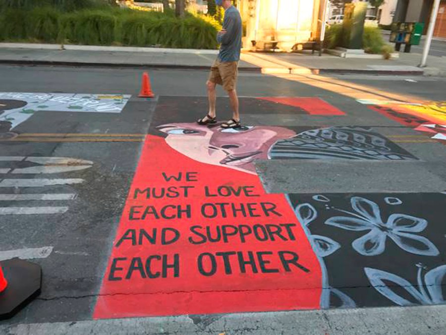 In this photo provided by the Palo Alto Daily Post, a man walks by a Black Lives Matter mural showing Assata Shakur, who was convicted of killing a New Jersey law enforcement officer in 1973, on July 8, 2020, in Palo Alto, Calif. Five police officers have filed a lawsuit against the city of Palo Alto for allowing the creation of the mural they say contained anti-police images. (Dave Price/Palo Alto Daily Post via AP)