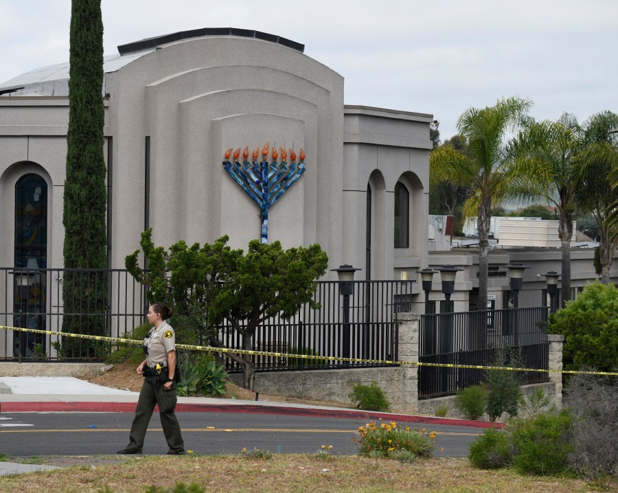 In this Sunday, April 28, 2019 file photo, a San Diego county sheriff's deputy stands in front of the Chabad of Poway synagogue, in Poway, Calif. A California judge on Wednesday, July 7, 2021 decided victims of the 2019 synagogue shooting near San Diego that killed one worshiper and wounded three can sue the manufacturer of the semiautomatic rifle and the gun shop that sold it to the teenage gunman, according to a newspaper report.(AP Photo/Denis Poroy, File)