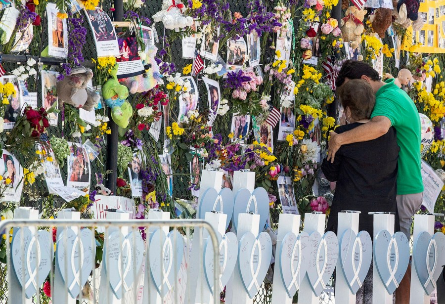 In this Thursday July 8, 2021, file photo, people mourn at the memorial wall for the victims of the Champlain Towers South collapse, in Surfside, Fla. Families waiting in agony for news on relatives who were in the Florida condo building when it collapsed are turning to each other for support. (Pedro Portal/Miami Herald via AP, File)