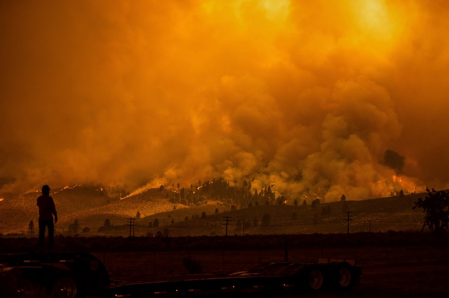 A truck driver who hauls fire equipment watches as the Sugar Fire, part of the Beckwourth Complex Fire, burns in Doyle, Calif., on Saturday, July 10, 2021. (AP Photo/Noah Berger)