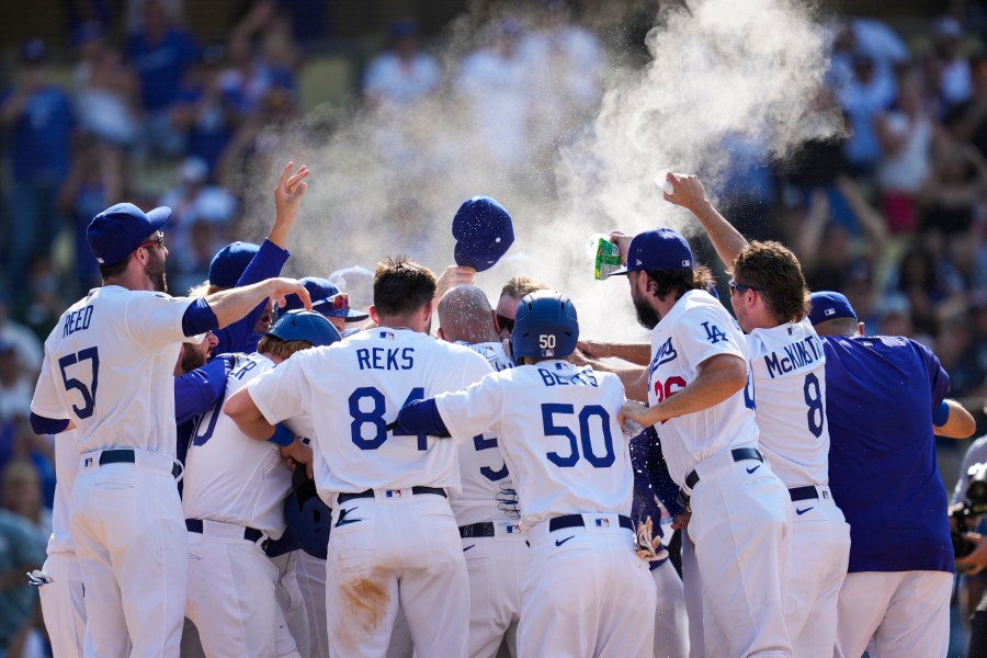 The Los Angeles Dodgers celebrate after Max Muncy hit a home run during the ninth inning of a baseball game against the Arizona Diamondbacks Sunday, July 11, 2021, in Los Angeles. Zach Reks and Mookie Betts also scored. The homer won the game for the Dodgers 7-4. (AP Photo/Ashley Landis)