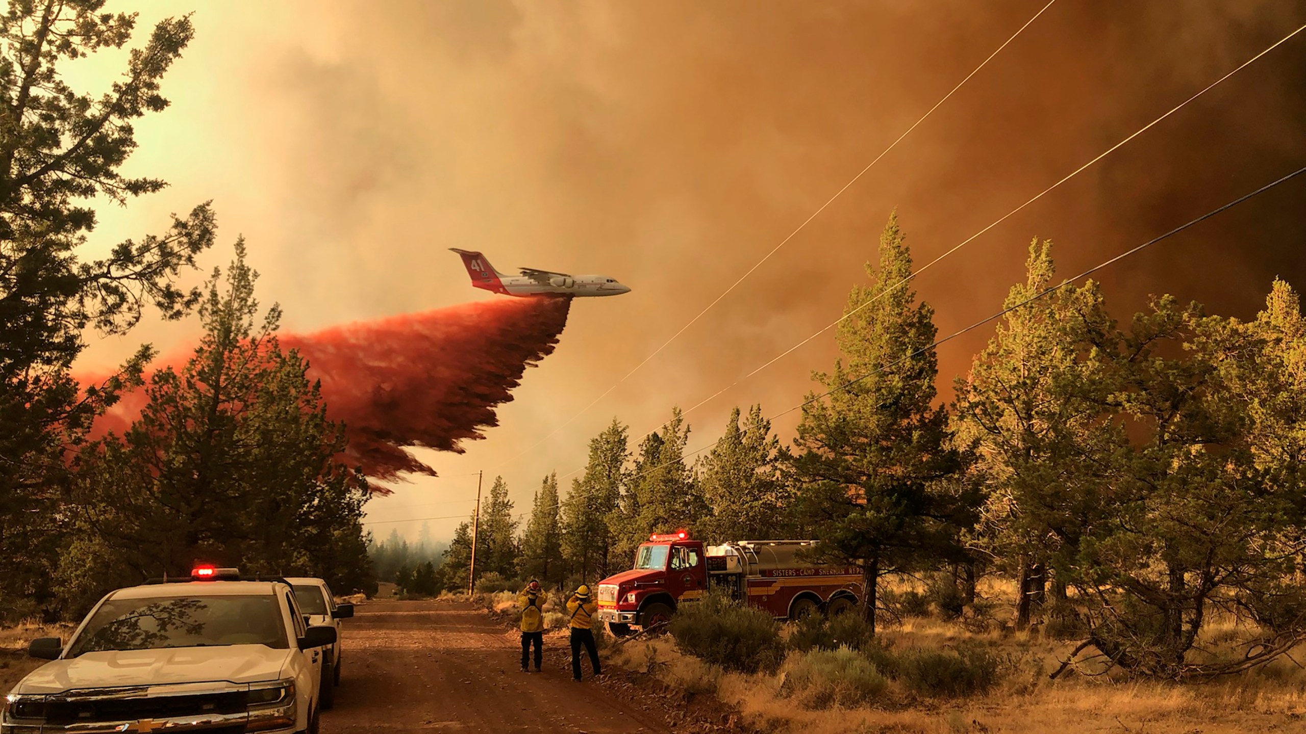 This photo provided by the Oregon Department of Forestry shows a firefighting tanker making a retardant drop over the Grandview Fire near Sisters, Ore., Sunday, July 11, 2021. The wildfire doubled in size to 6.2 square miles (16 square kilometers) Monday, forcing evacuations in the area, while the state's biggest fire continued to burn out of control, with containment not expected until November. (Oregon Department of Forestry via AP)