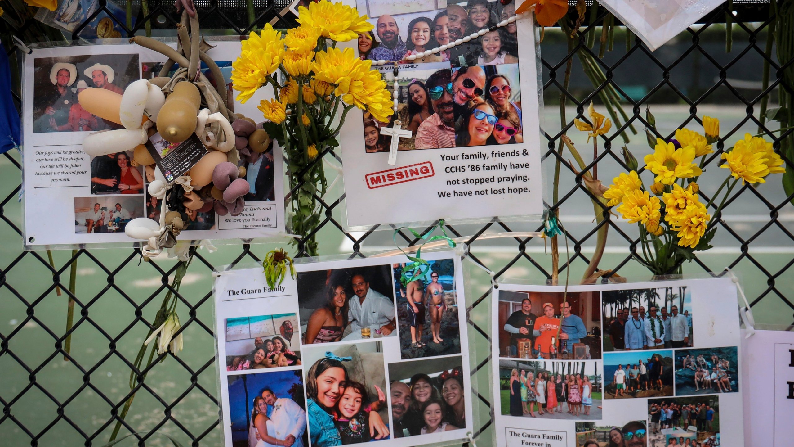 In this July 6, 2021, file photo, a memorial for the Guara family is posted on a fence near the Champlain Towers South, in Surfside, Fla. Recovery crews at the Florida condominium collapse are cataloging all personal possessions found in the rubble in hopes of returning them to families of the dead or survivors. (Carl Juste/Miami Herald via AP, File)