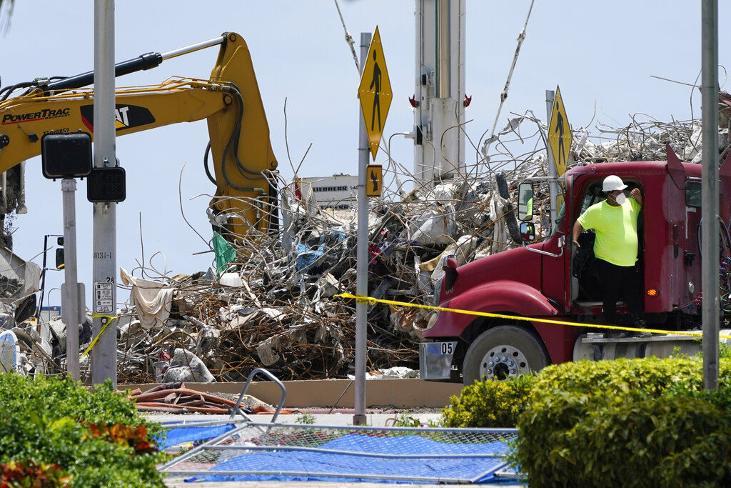 A worker waits to load his truck with debris from the rubble of the Champlain Towers South building, as removal and recovery work continues at the site of the partially collapsed condo building, Wednesday, July 14, 2021, in Surfside, Fla. (AP Photo/Lynne Sladky)