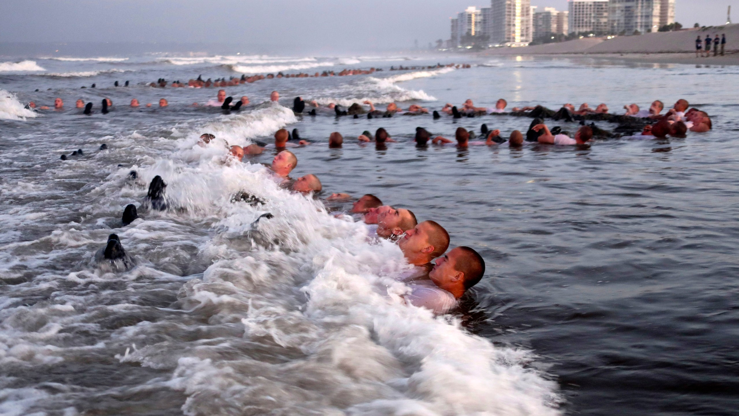 In this May 4, 2020 photo provided by the U.S. Navy, SEAL candidates participating in "surf immersion" during Basic Underwater Demolition/SEAL (BUD/S) training at the Naval Special Warfare (NSW) Center in Coronado, Calif. For the first time, a female sailor has successfully completed the grueling 37—week training course to become a Naval Special Warfare combatant-craft crewman — the boat operators that transport Navy SEALs and conduct their own missions at sea. Navy officials said they would not identify the woman, who completed the final phases of training and graduated Thursday. She was one of 17 sailors to receive their pins during the ceremony. (MC1 Anthony Walker/U.S. Navy via AP)